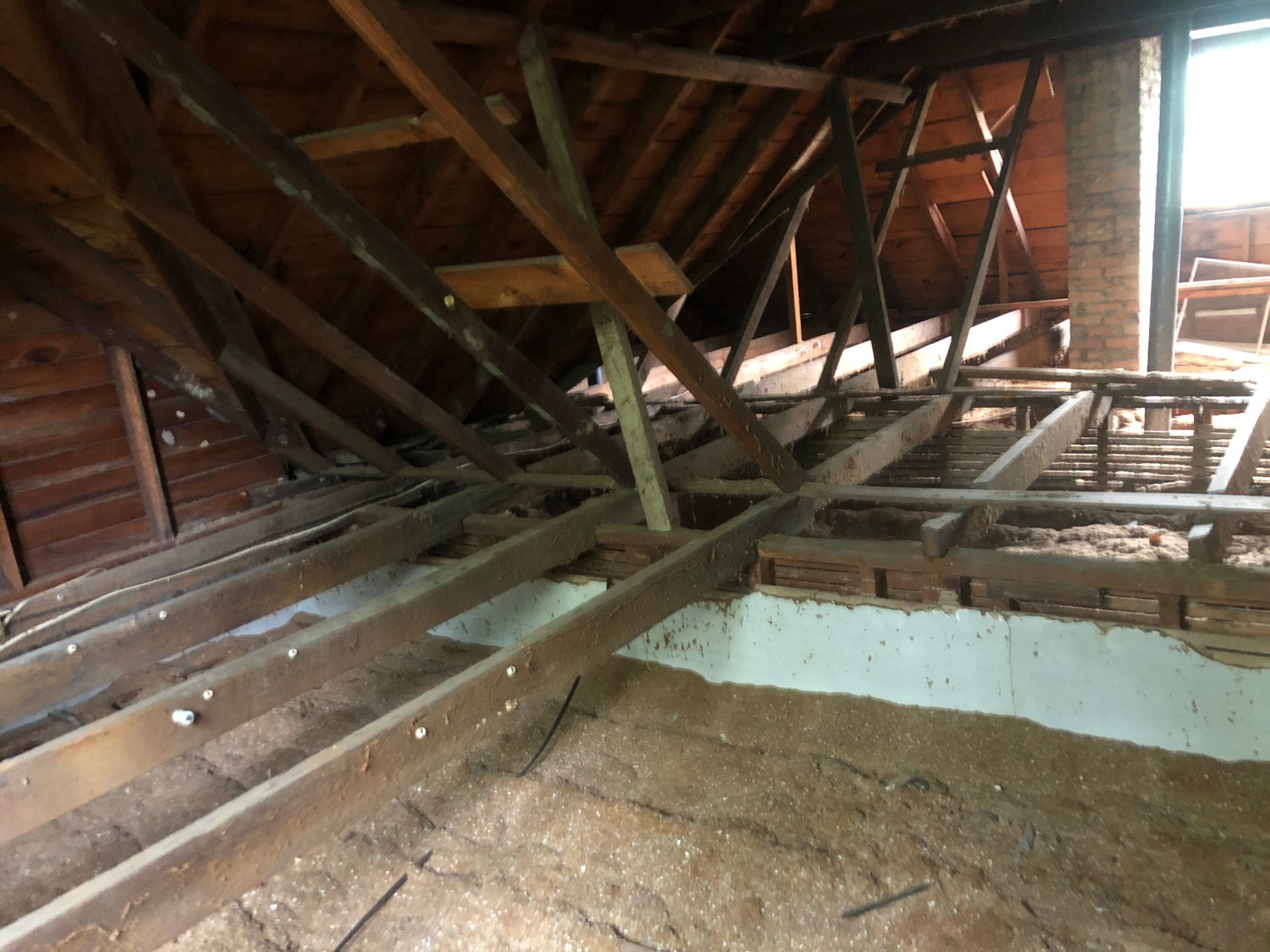 Collapsed attic with broken wooden beams and debris inside a damaged roof structure