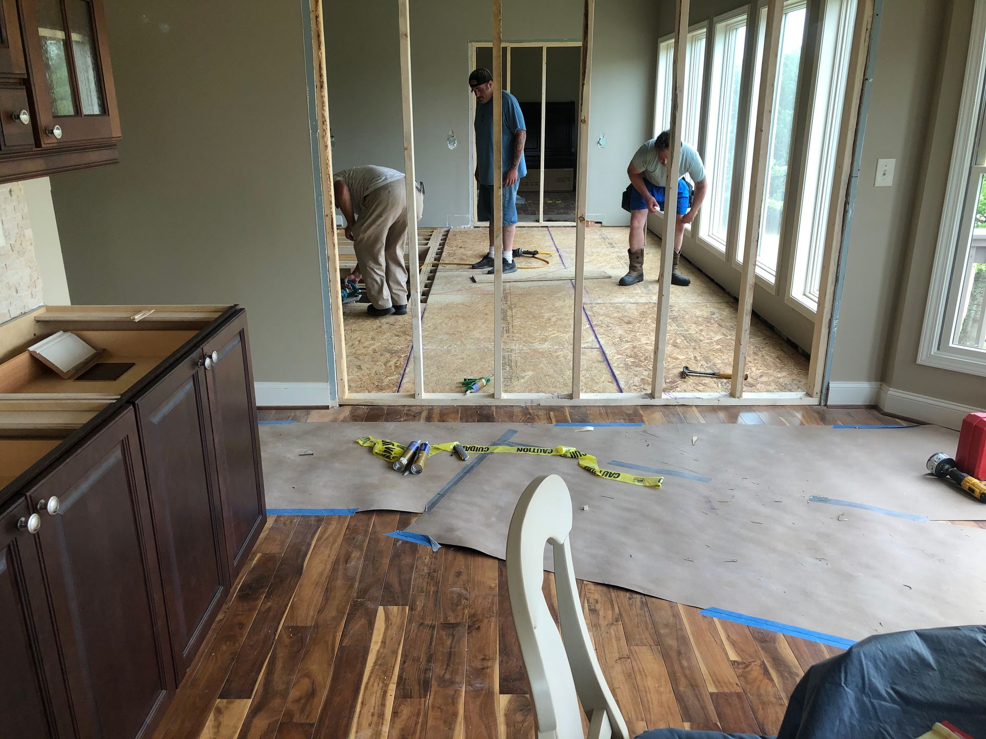 Interior renovation with exposed studs, tools, and two workers in a partially finished room