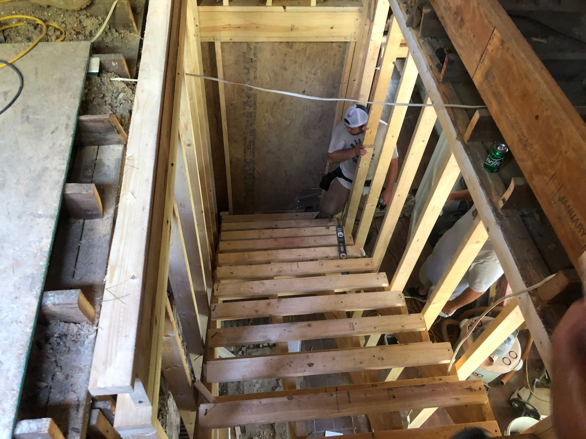 Wood-framed staircase under construction with unfinished steps and railings viewed from above