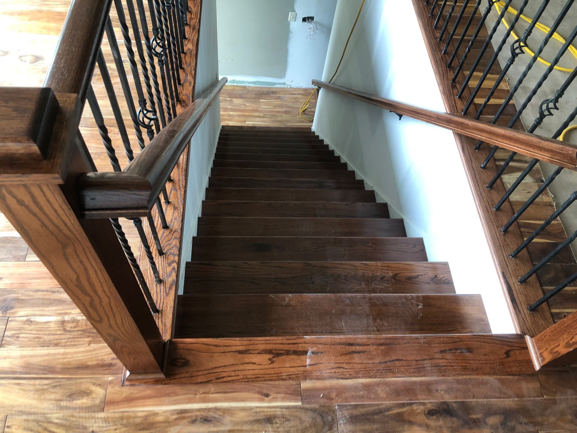 Wooden staircase with dark steps and black railings in a narrow interior hallway.