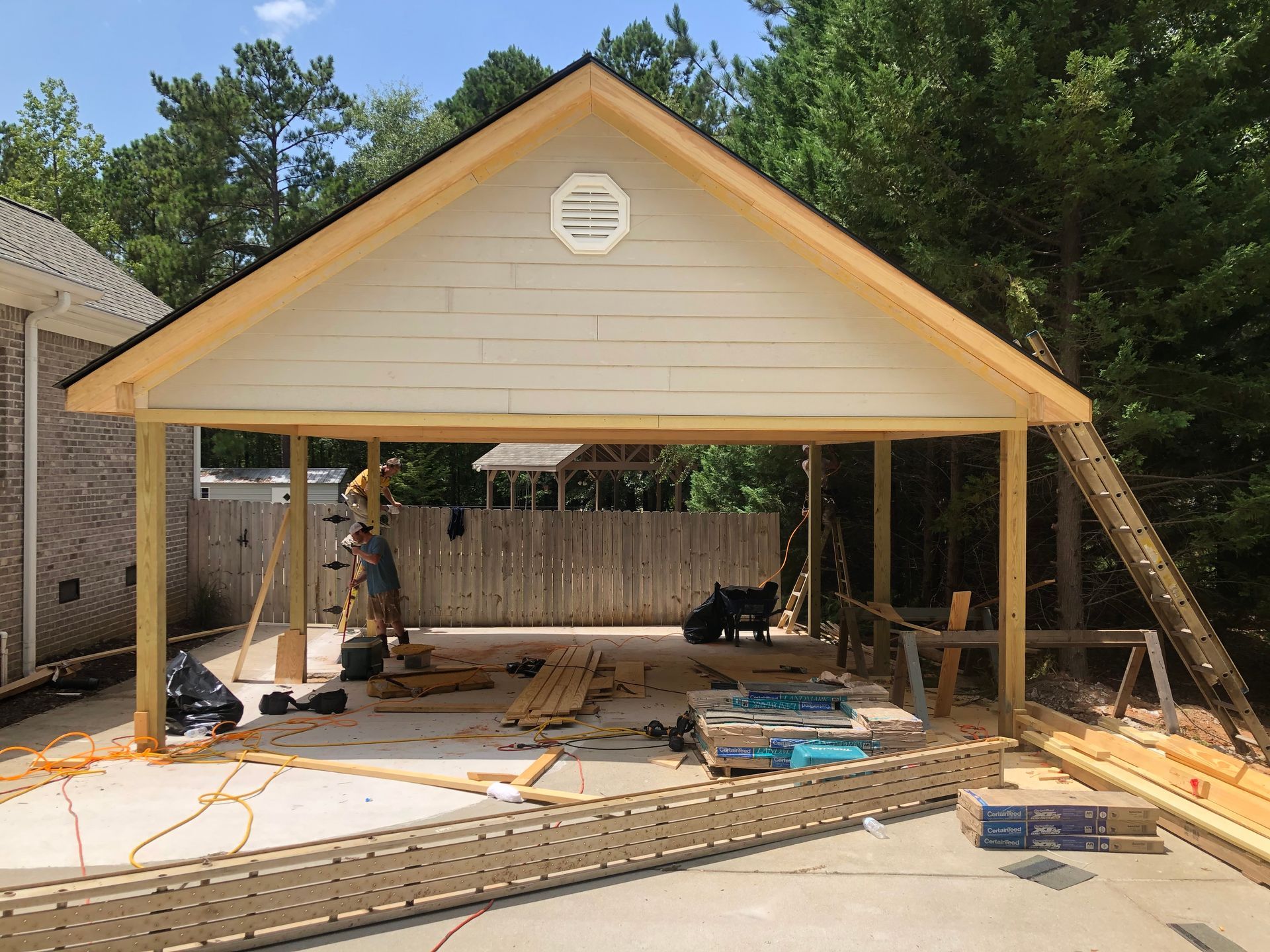 Front view of a beige detached garage under construction, with exposed framing and building materials on the slab.