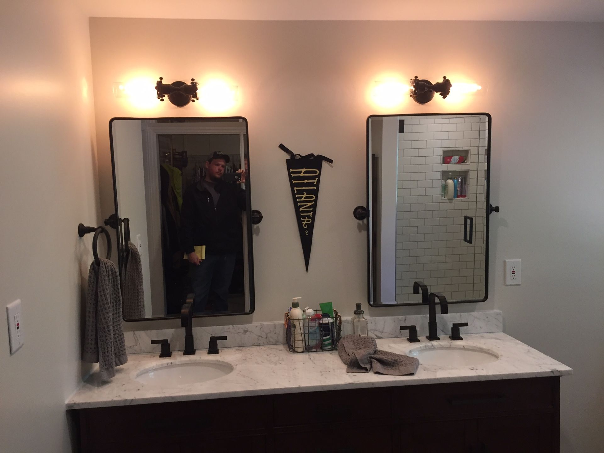 Bathroom vanity with two mirrors and wall sconces, light countertop, and towels hanging on the left.