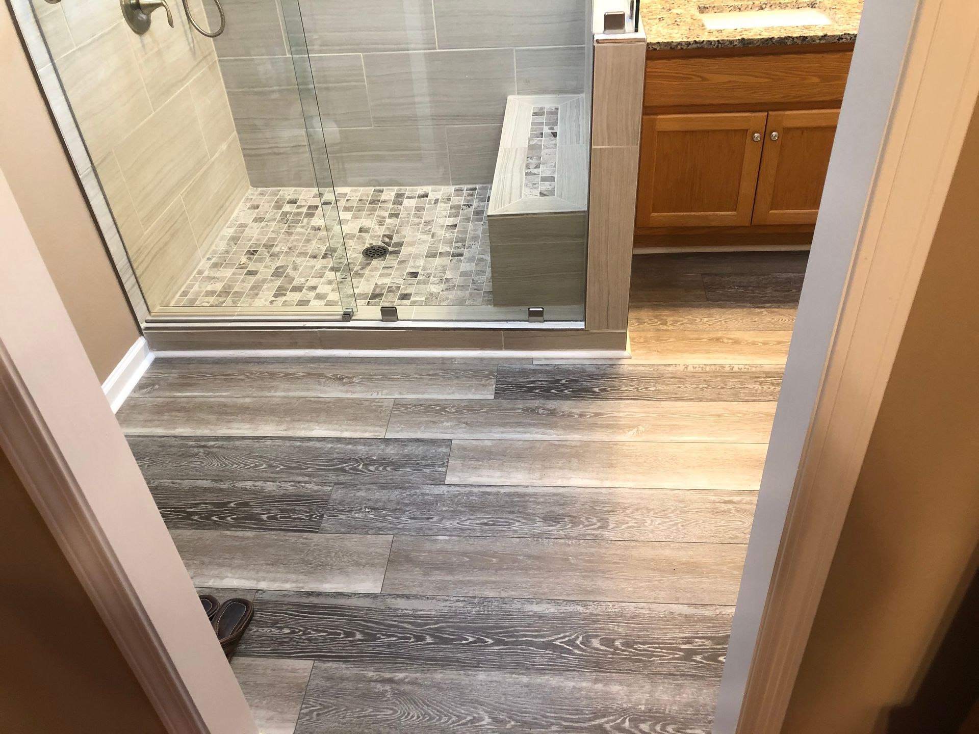 Bathroom entrance with wood-look flooring and a tiled shower area with a glass door