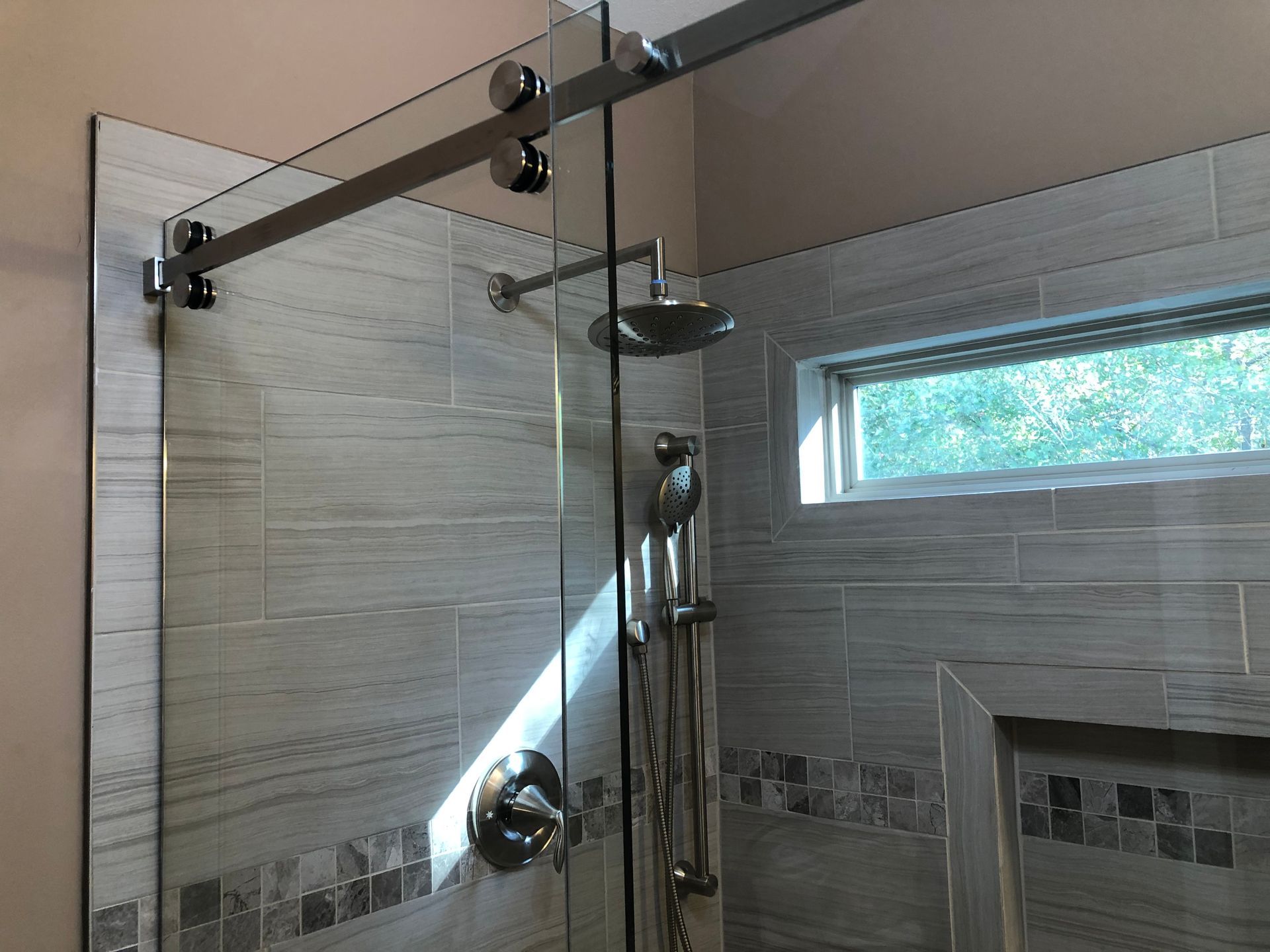 Glass shower enclosure with chrome fixtures and tiled bathroom walls