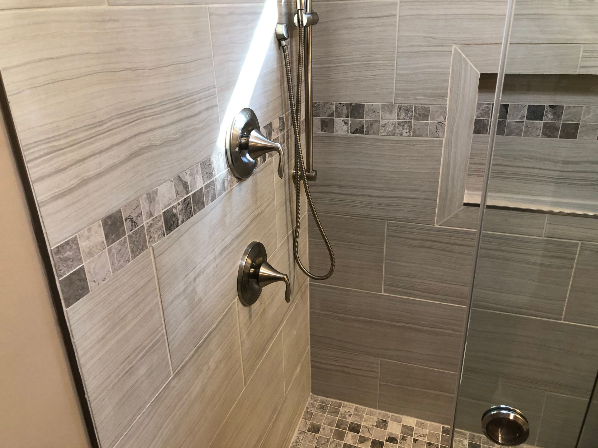 Bathroom shower with tiled walls, glass door, and chrome fixtures