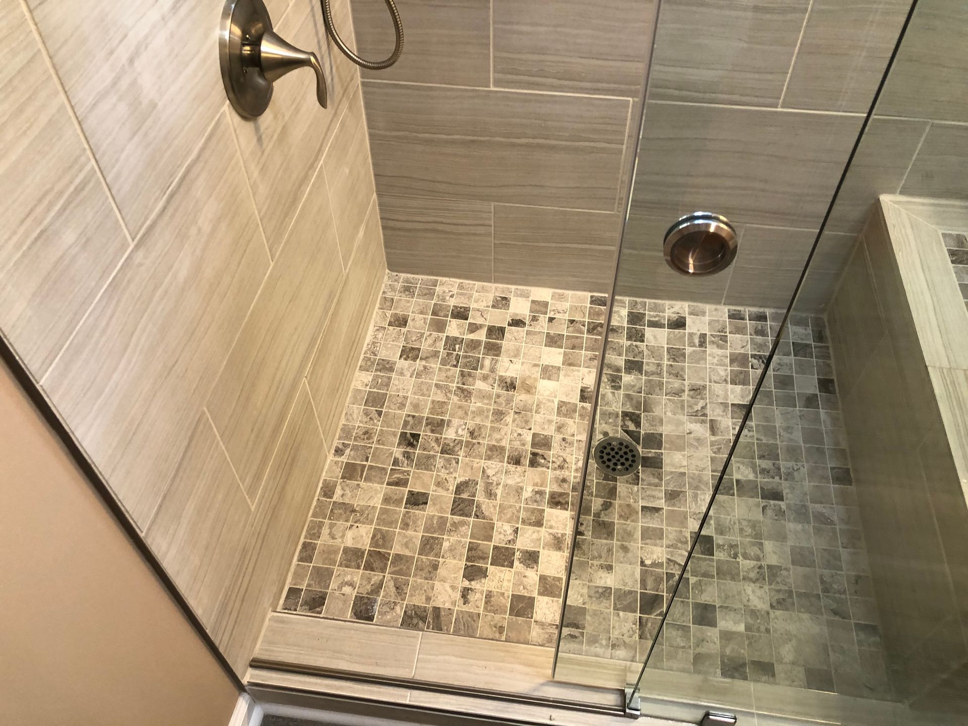 Walk-in shower with tiled floor, glass partition, and wall-mounted showerhead.
