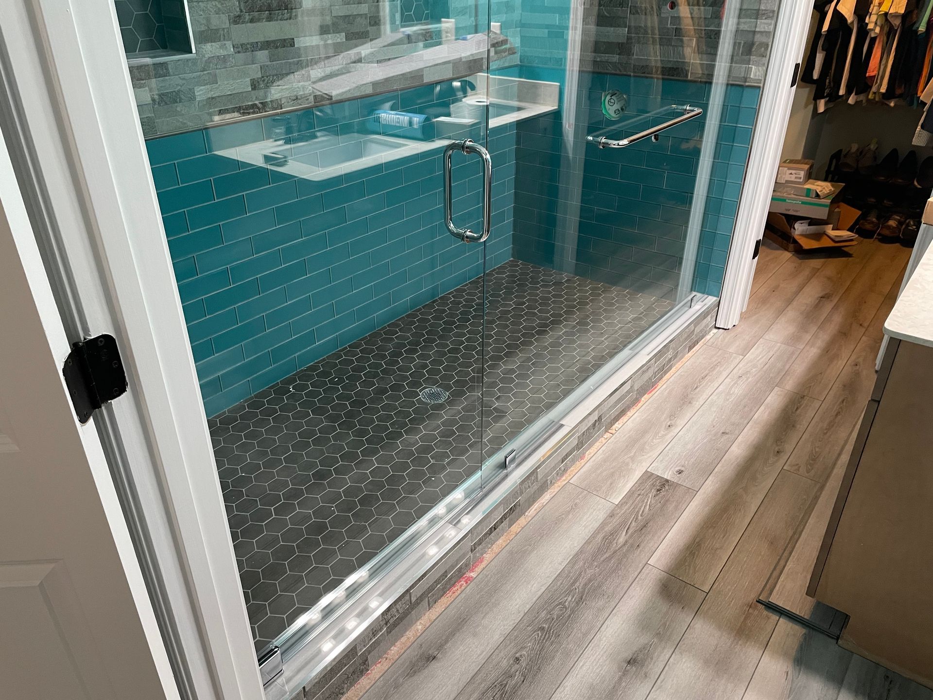 Glass shower enclosure beside a wood-look floor in a modern bathroom