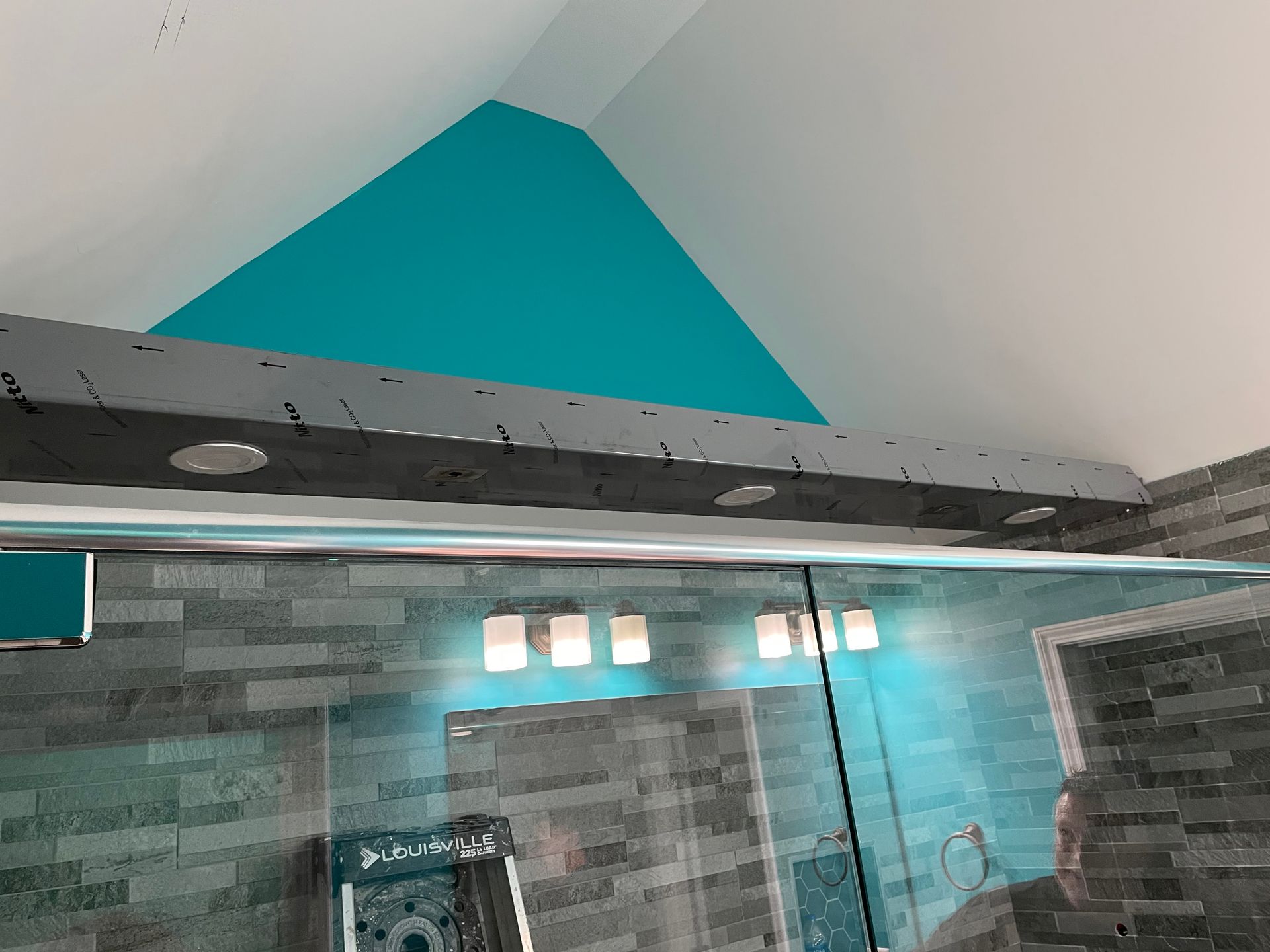 Bathroom with teal accent wall, white sloped ceiling, gray tile, and glass shower enclosure
