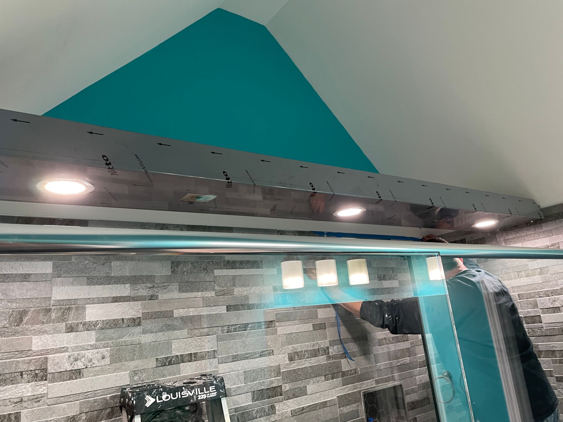 Bathroom with teal accent wall, gray tile backsplash, and mirrored cabinet with under-cabinet lights