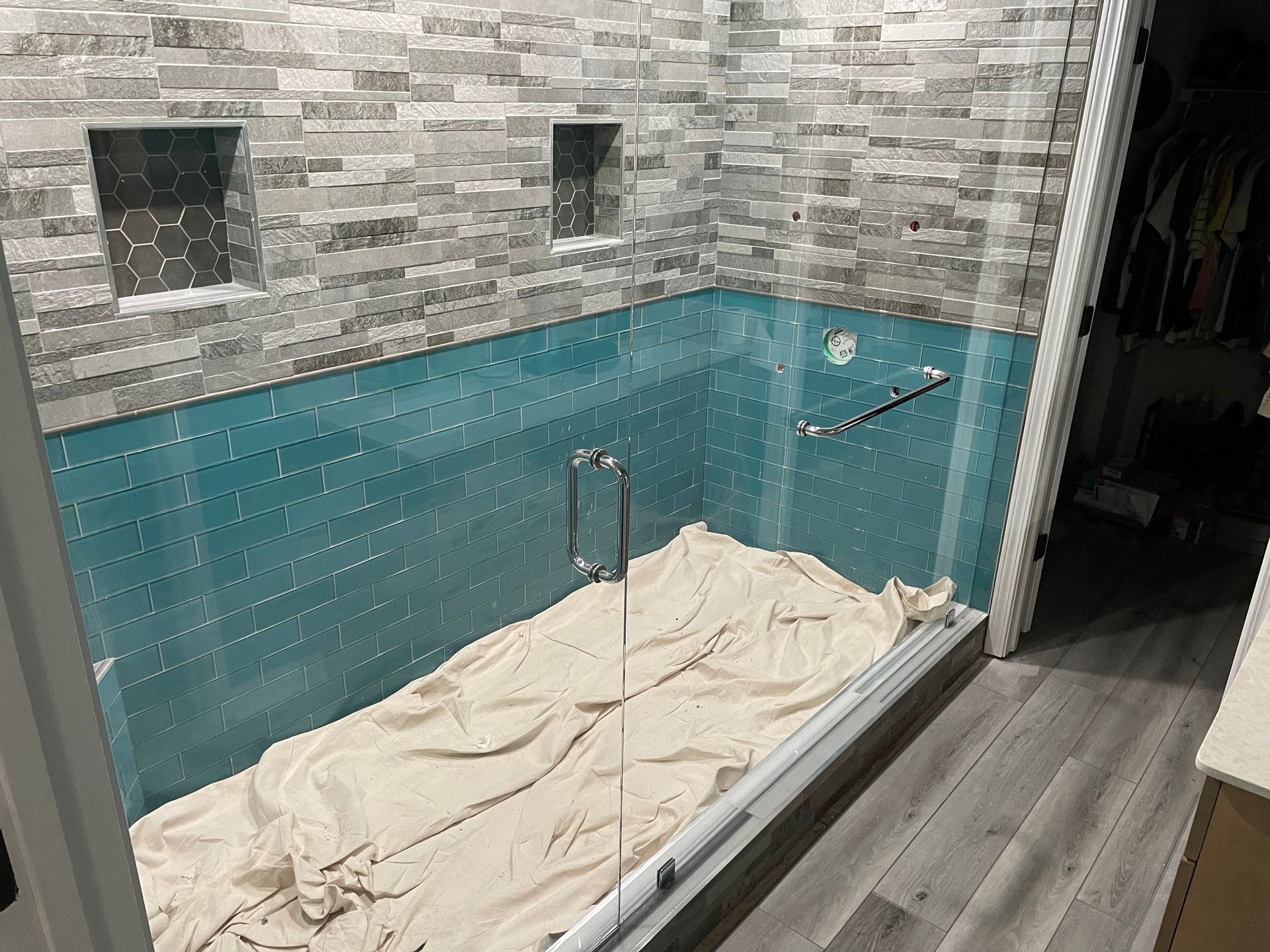 Small bathroom with a tiled wall, walk-in shower, and beige curtain over a bathtub.