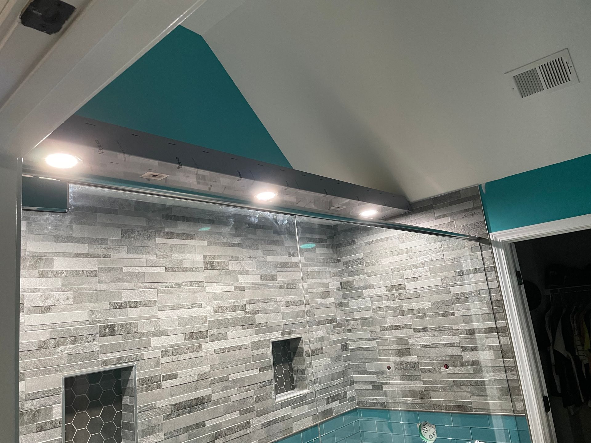Gray tiled wall with teal accents and recessed lights in a modern interior