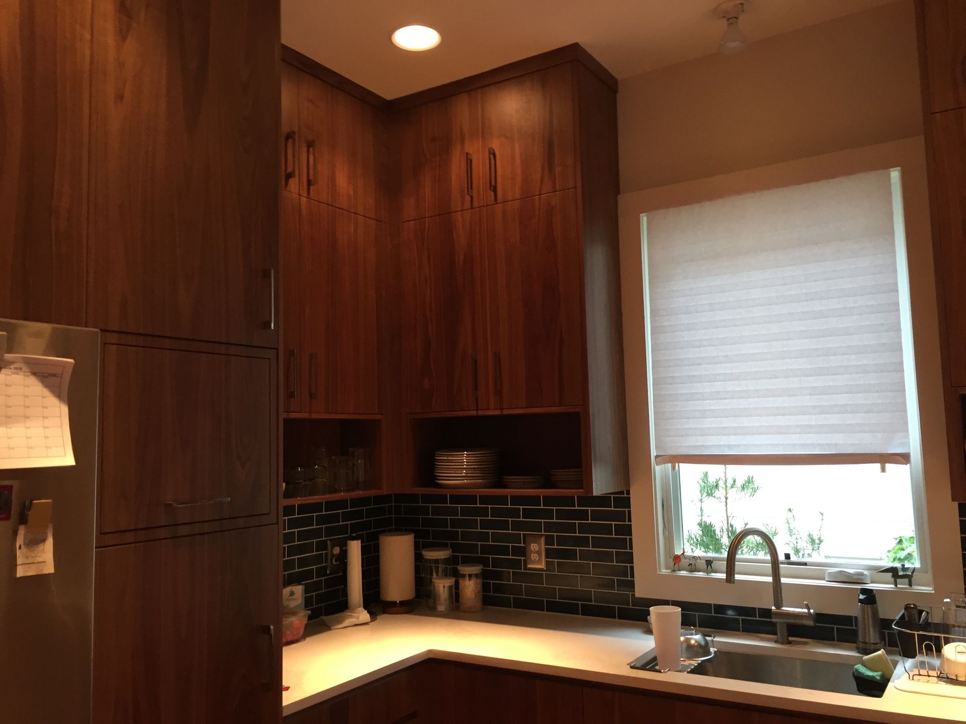 Modern kitchen with dark wood cabinets, black tile backsplash, and a sunlit window over the sink