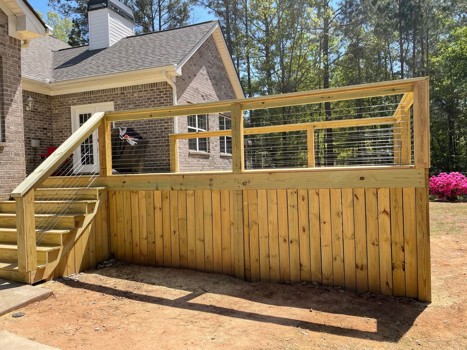 Wooden backyard deck with stairs and railing beside a brick house, under construction