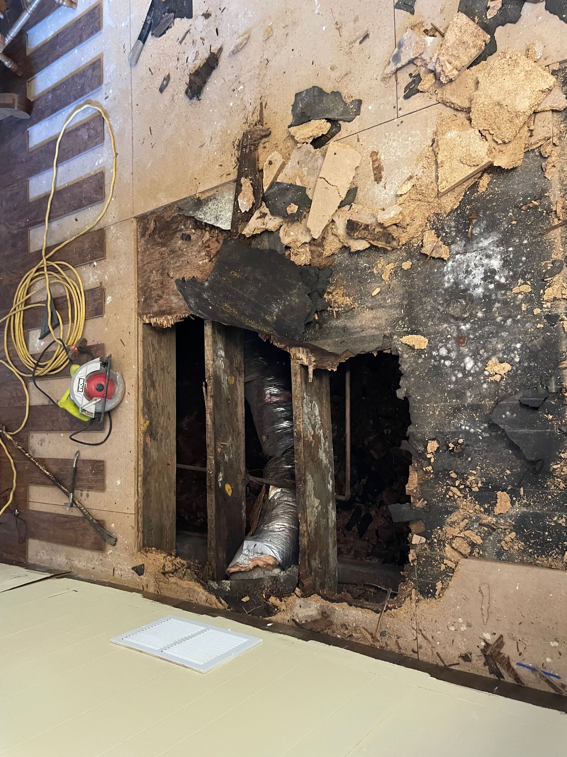 Severely charred wall with a damaged fireplace opening and burned debris inside