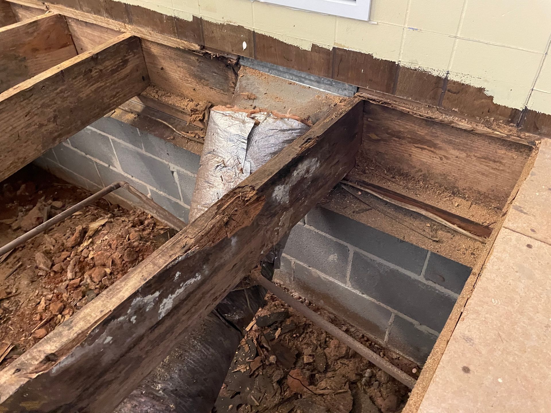 Damaged floor framing with exposed wooden beams and cinder blocks in a partially demolished room