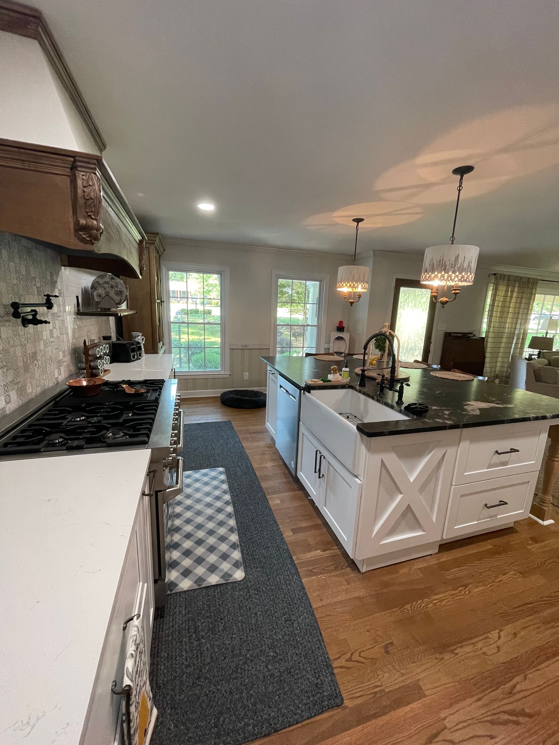 Bright modern kitchen with white cabinets, island, pendant lights, and a long runner rug