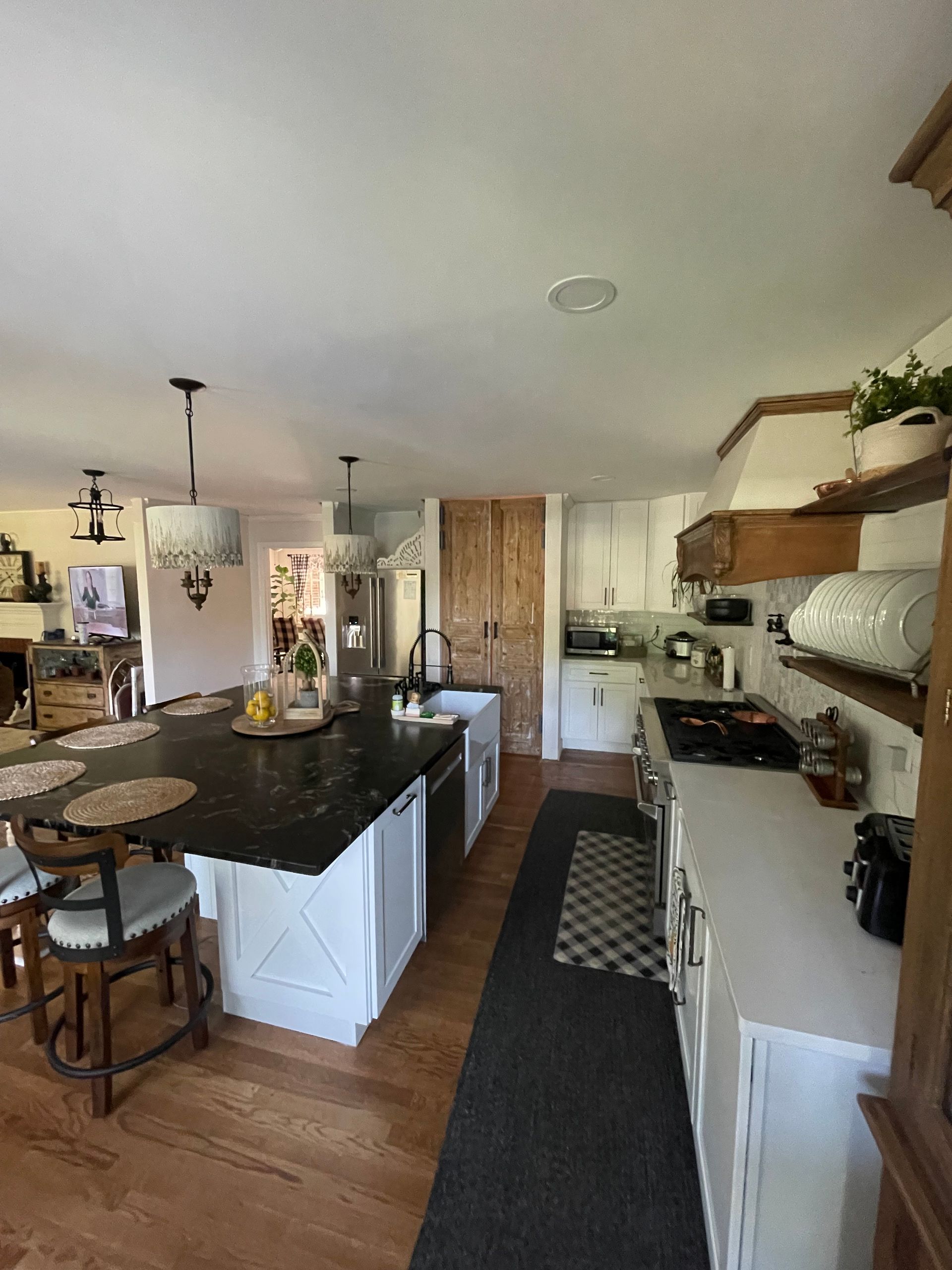 Bright, modern kitchen with white cabinets, black island, wood floors, and open shelving