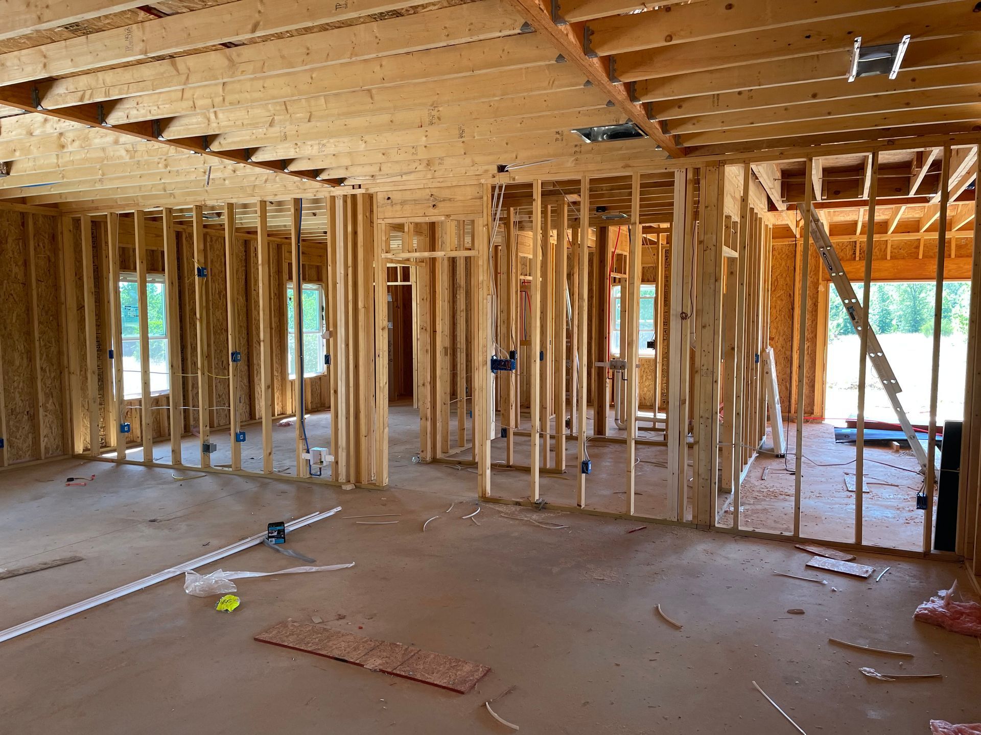 Interior of a house under construction with exposed wooden framing and unfinished floors and ceiling