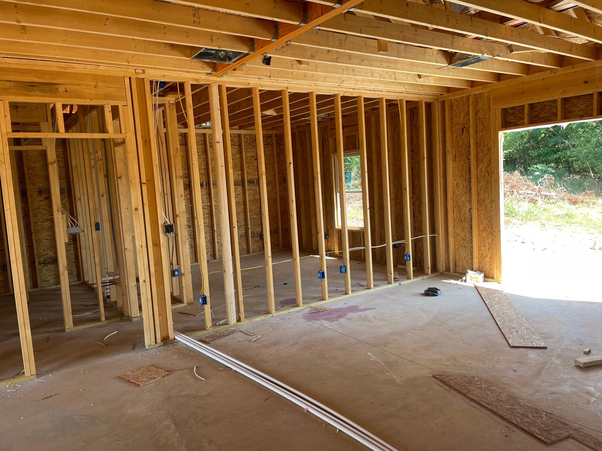 Unfinished wooden house interior with exposed framing and open doorway to the outside.