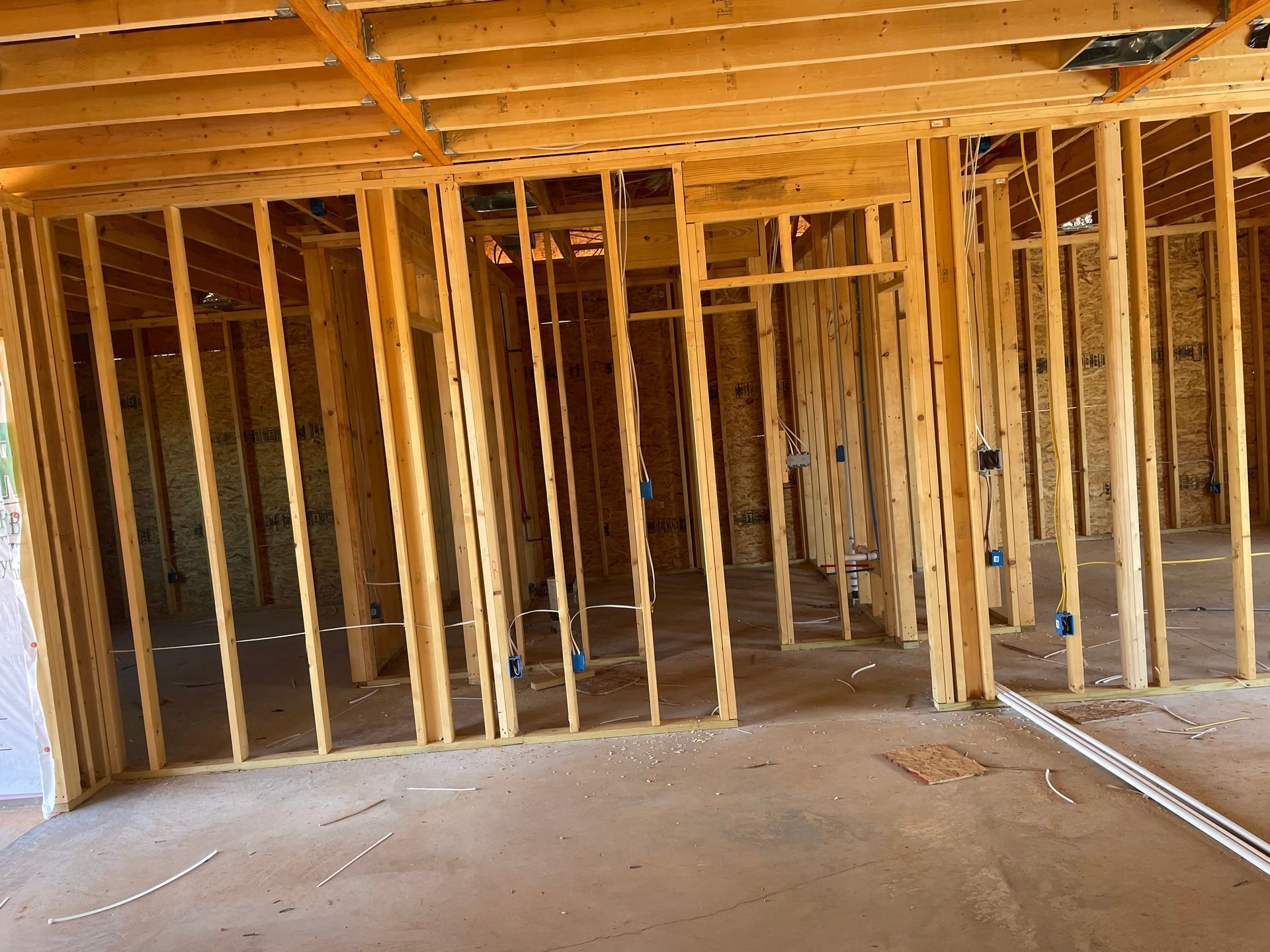 Interior of an unfinished house with exposed wooden framing and concrete floor