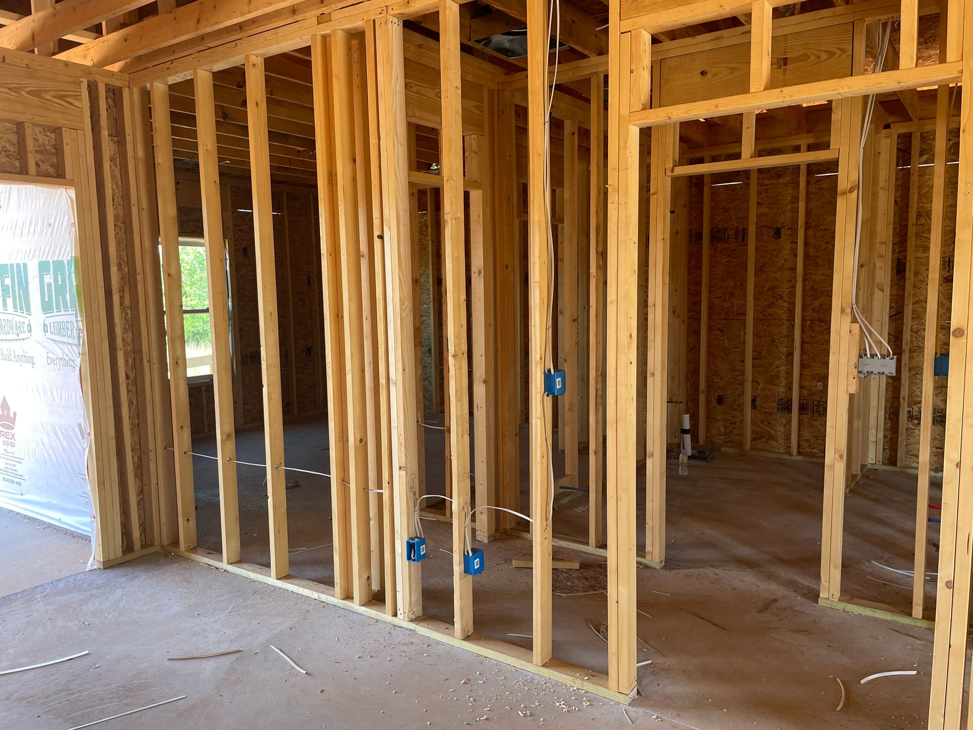 Wood-framed interior of a house under construction with exposed studs and unfinished floors