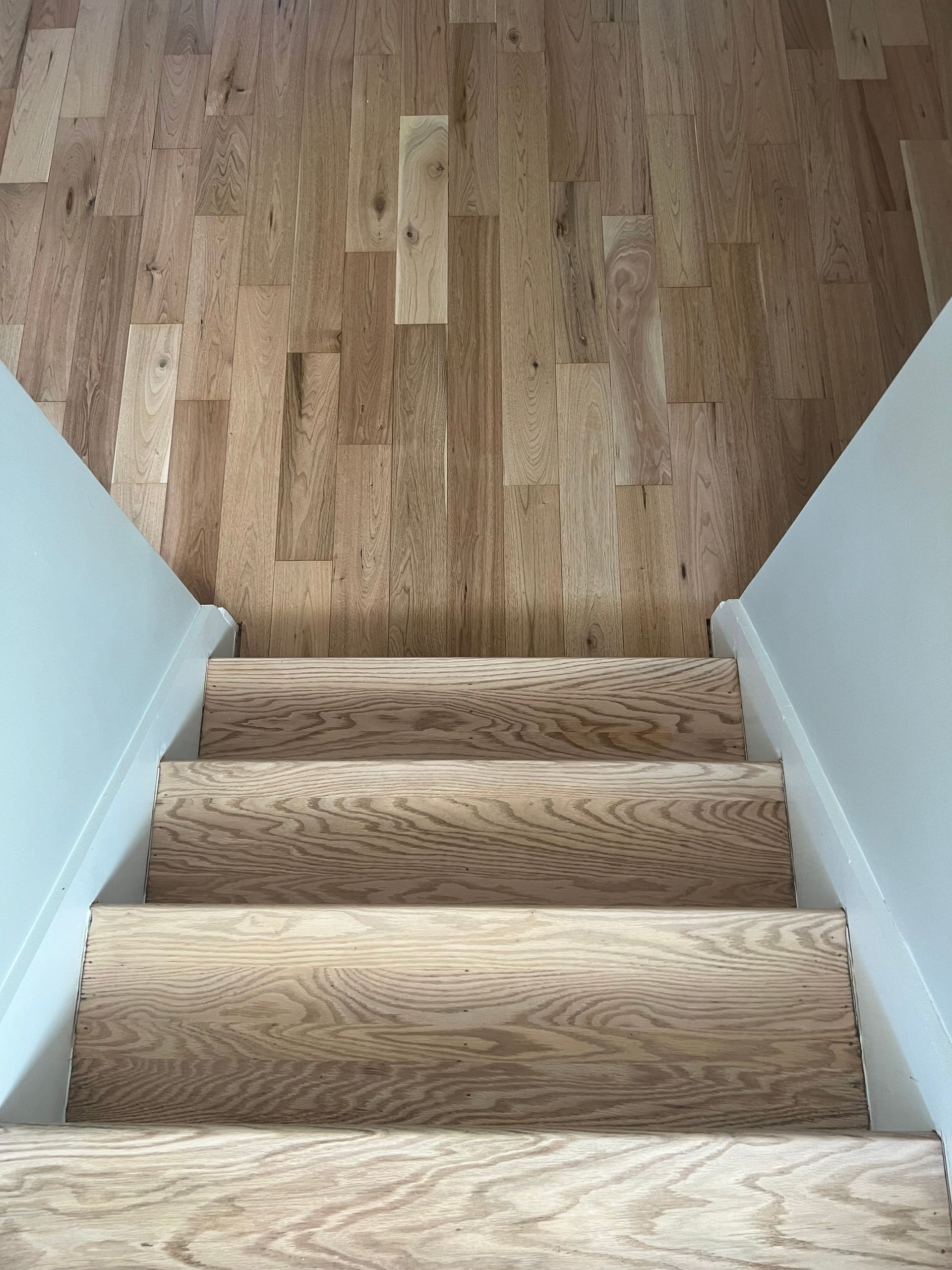 Wooden staircase leading up to a hardwood floor landing, viewed from above