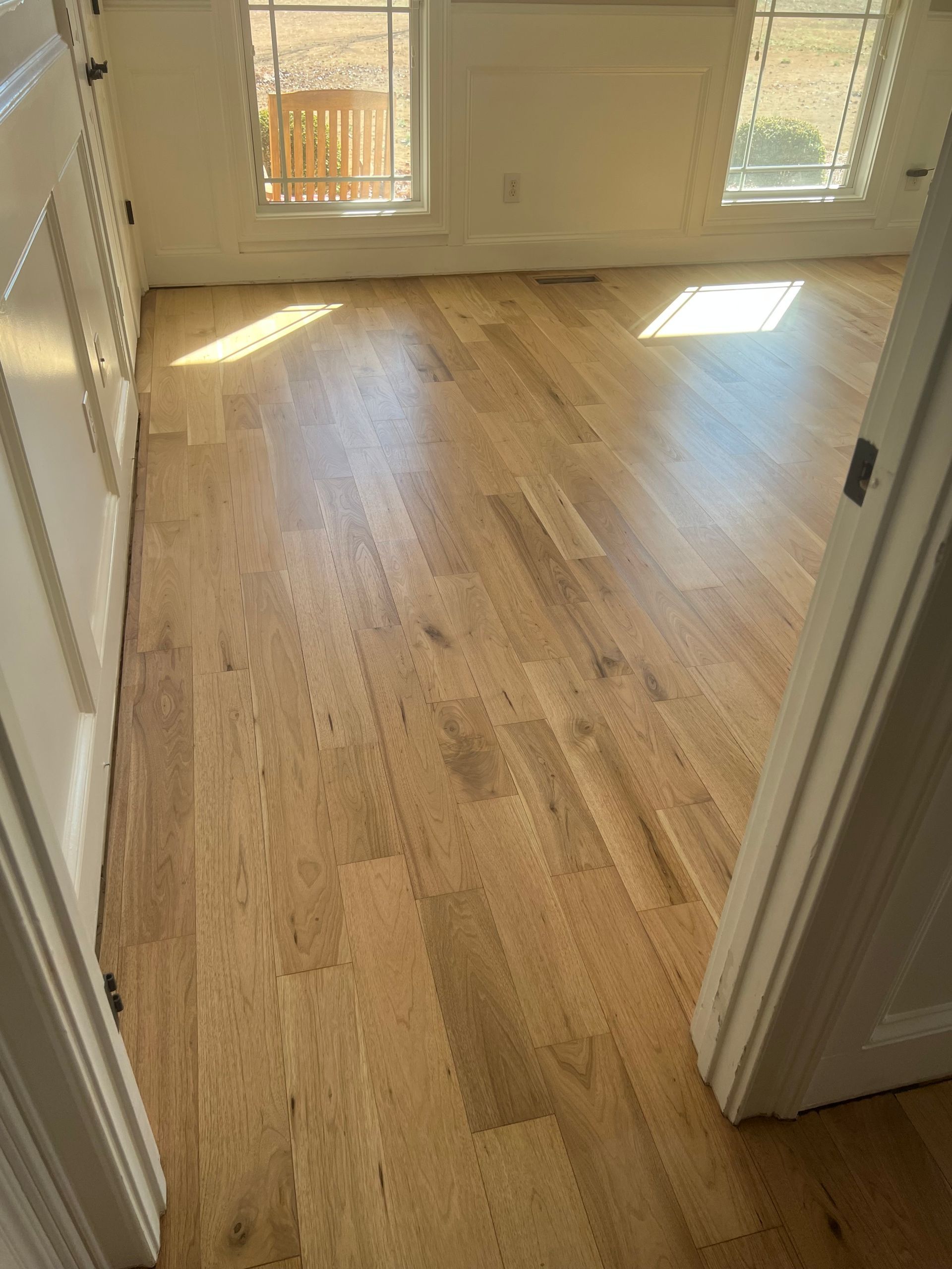 Empty room with light wood floors and sunlight from windows