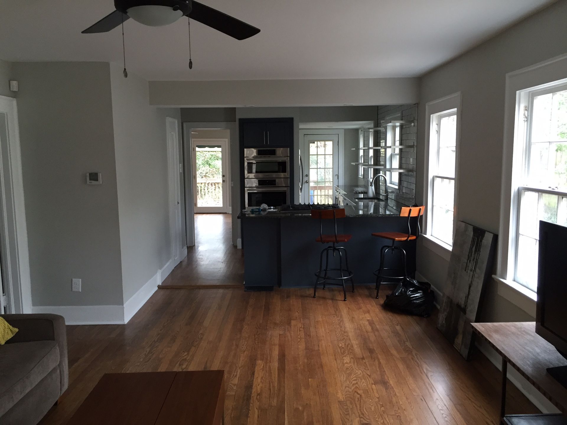 Open-concept living room and kitchen with wood floors, gray walls, island, and ceiling fan.