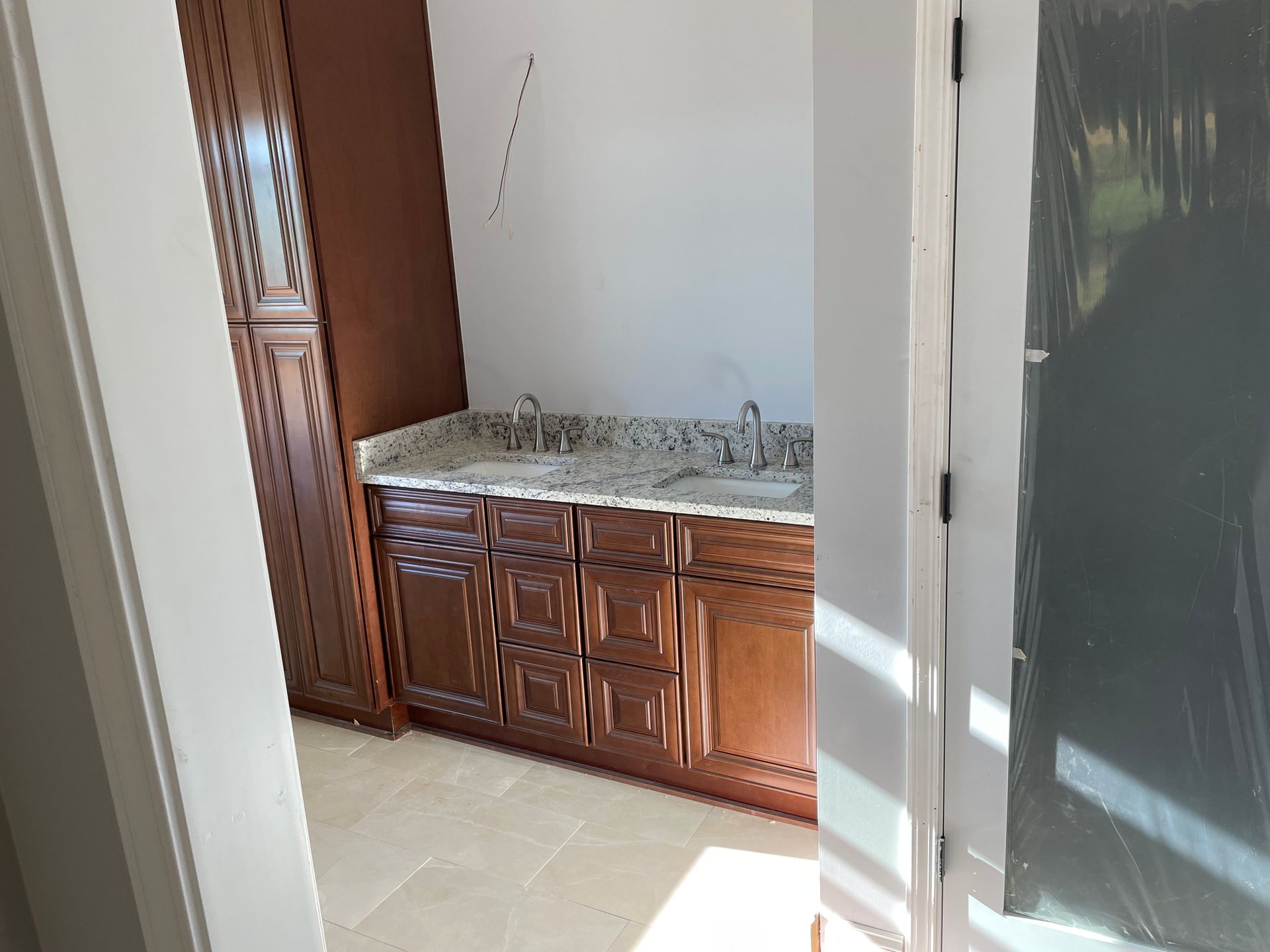 Small bathroom vanity with marble sink and wooden cabinets beside a shower stall.