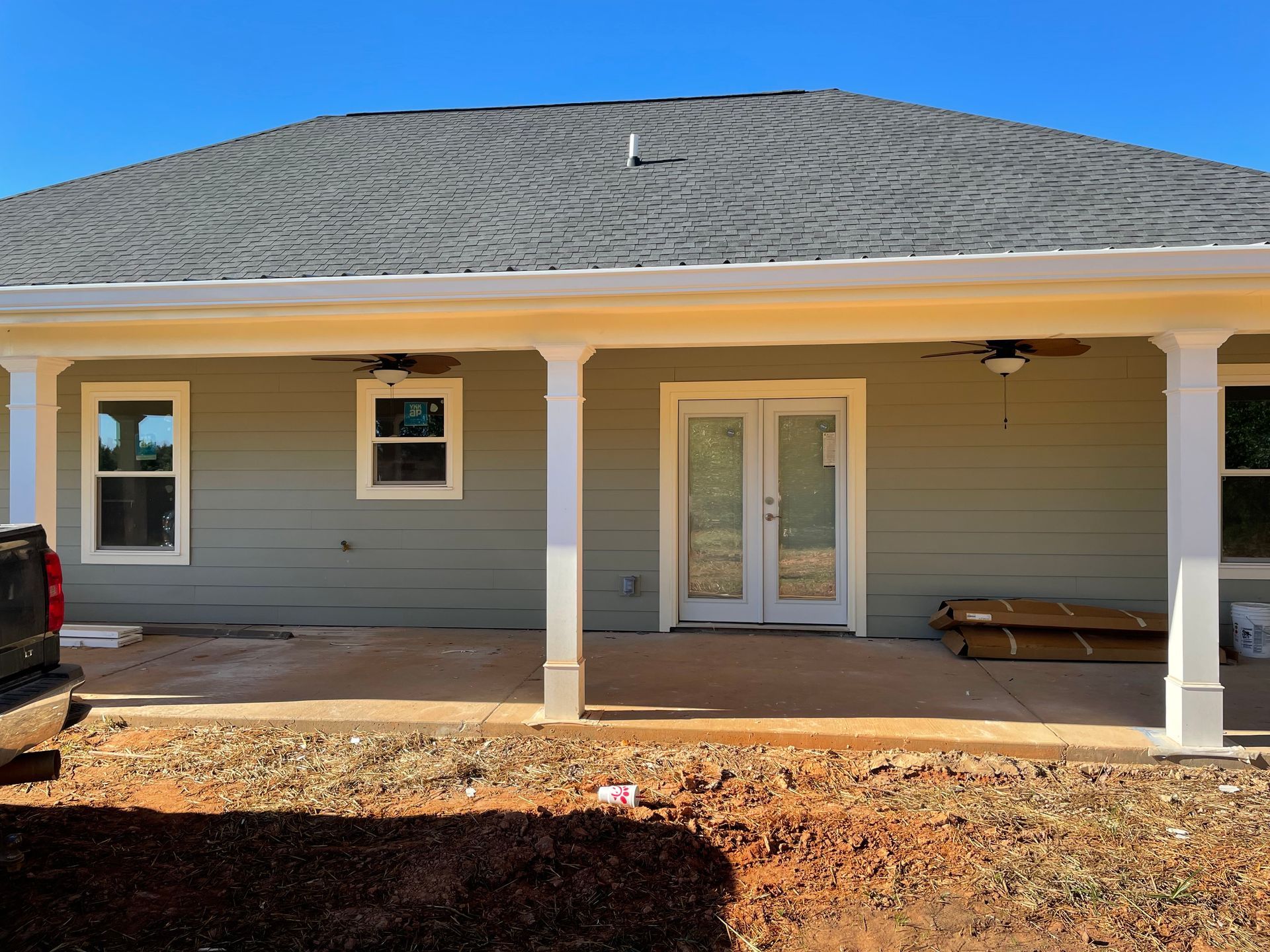 Front view of a gray house with white trim, covered porch, and double front doors under construction