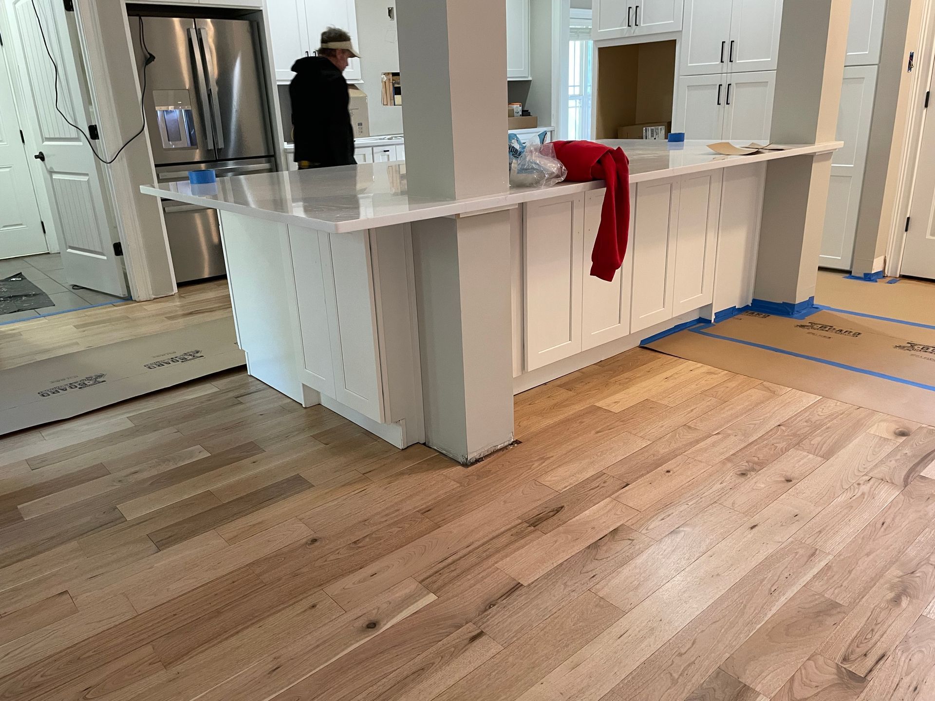 Bright kitchen with white island, hardwood floor, and a red towel draped over the counter.