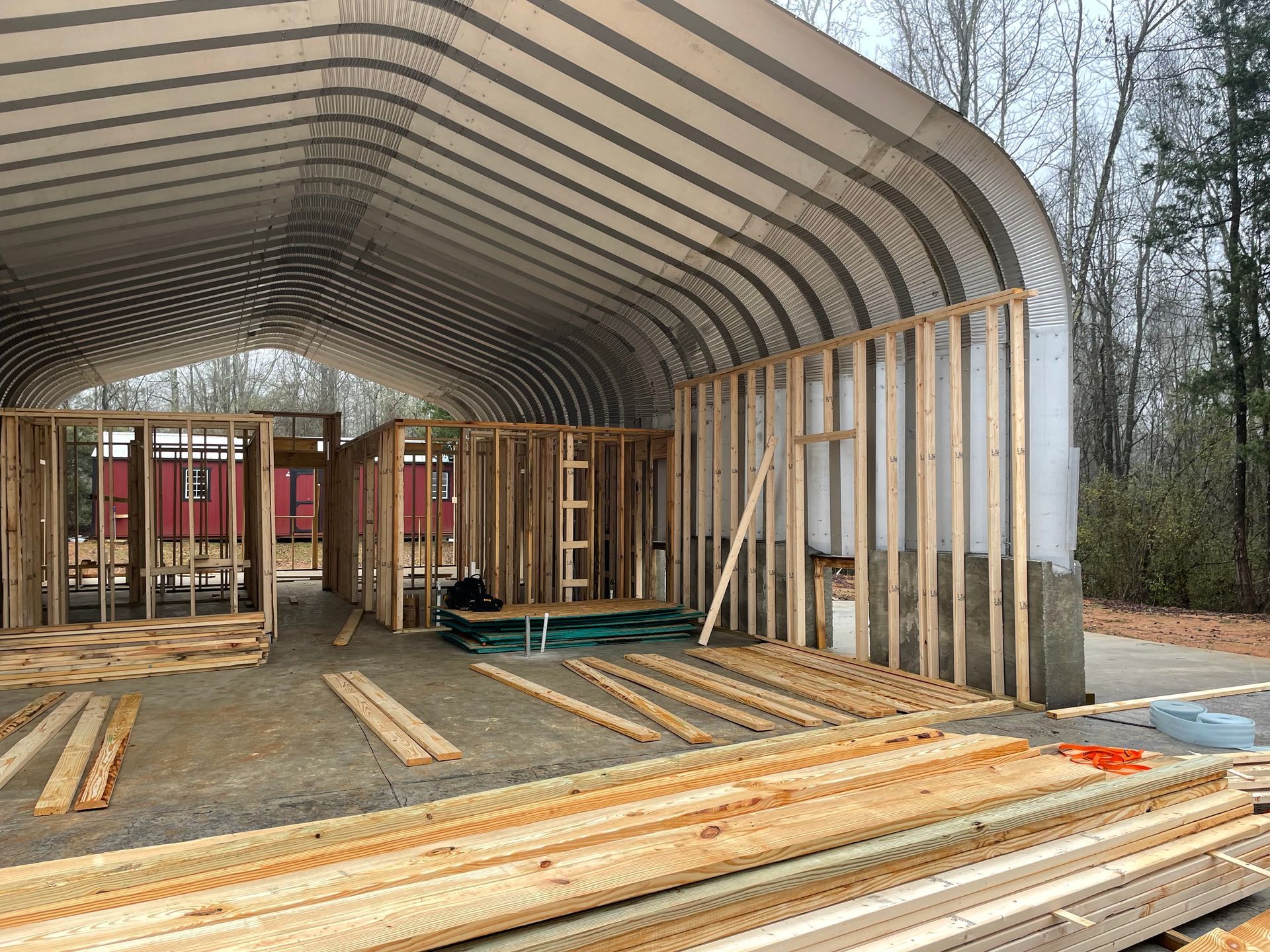 Partially built wooden house frame with arched metal roof under construction