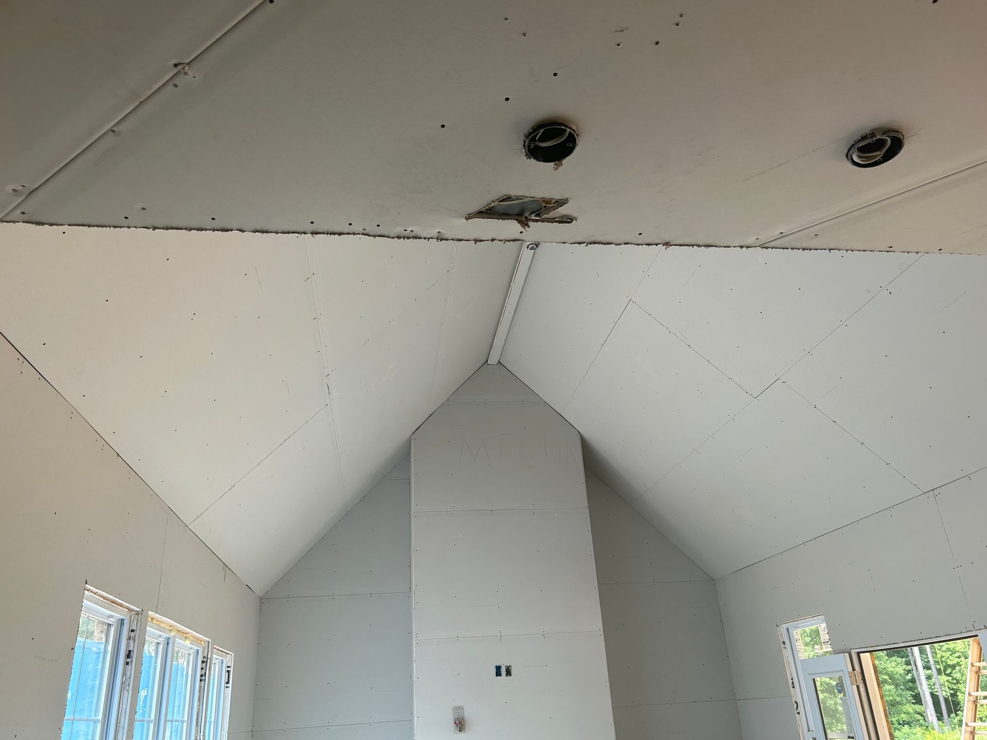 Interior of a white unfinished room with a tall central chimney and sloped ceiling under construction