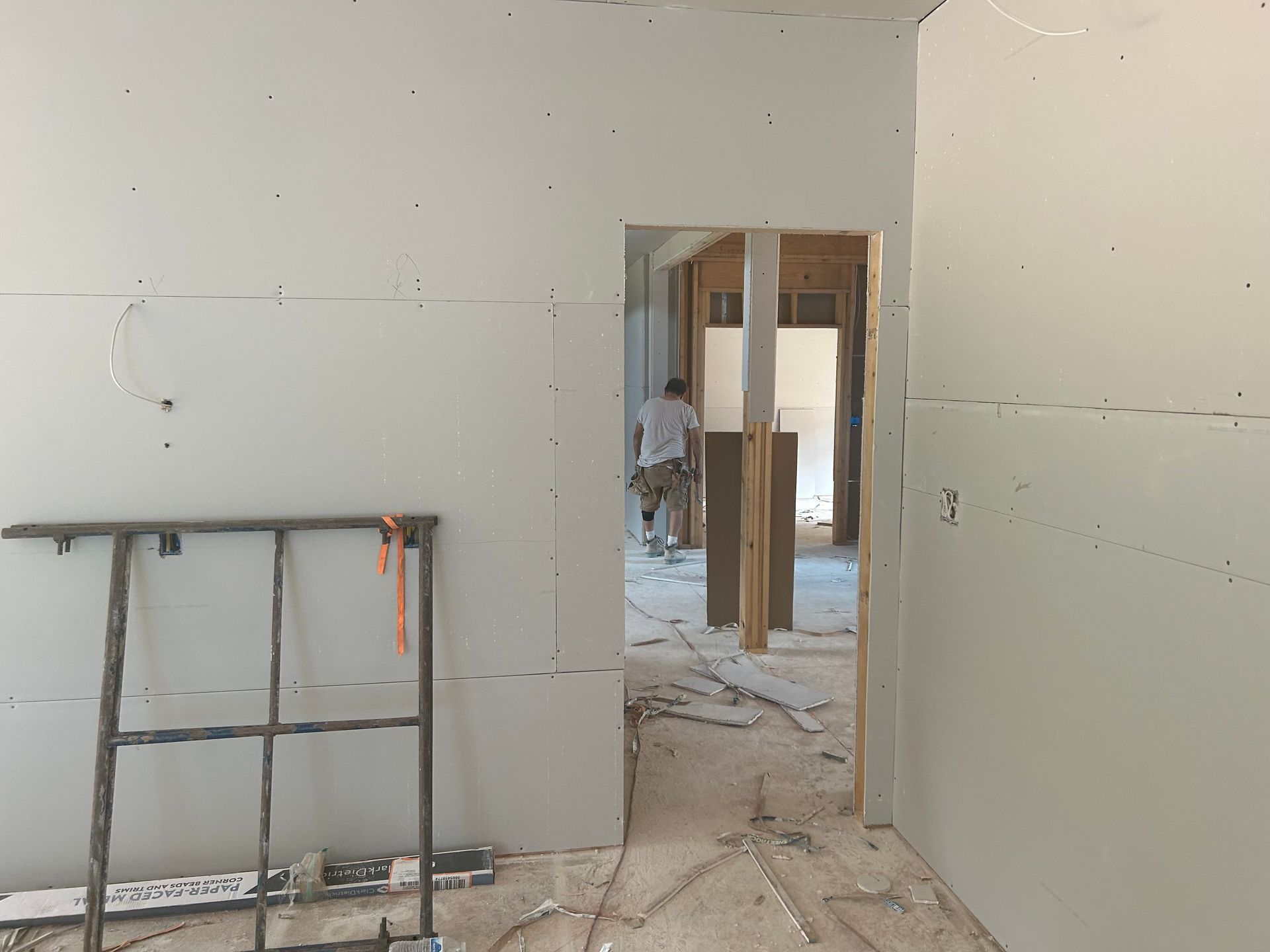 Interior under renovation with unfinished drywall, tools, and a doorway to another room