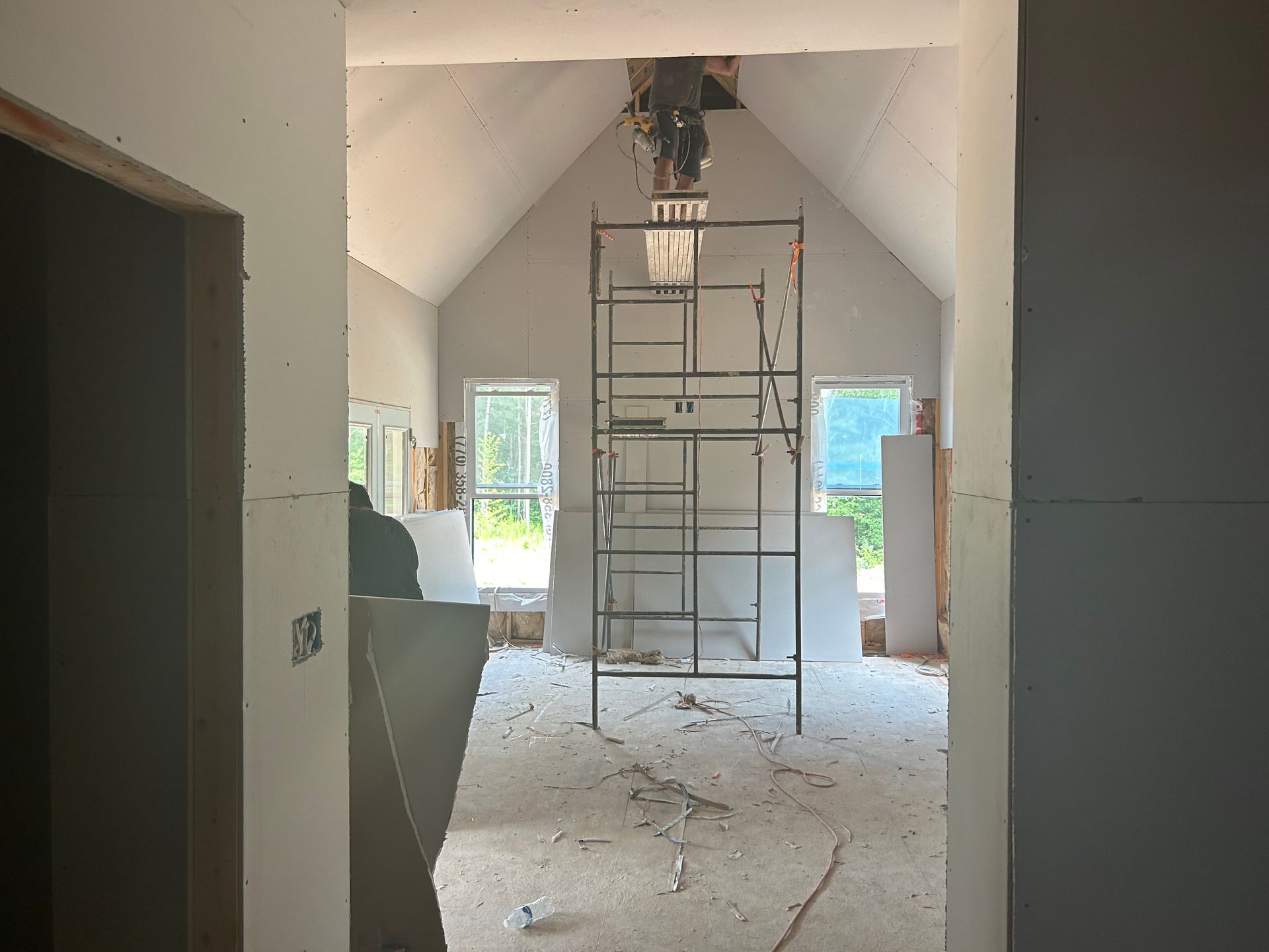 Renovation site with scaffolding in a white, unfinished room and debris on the floor