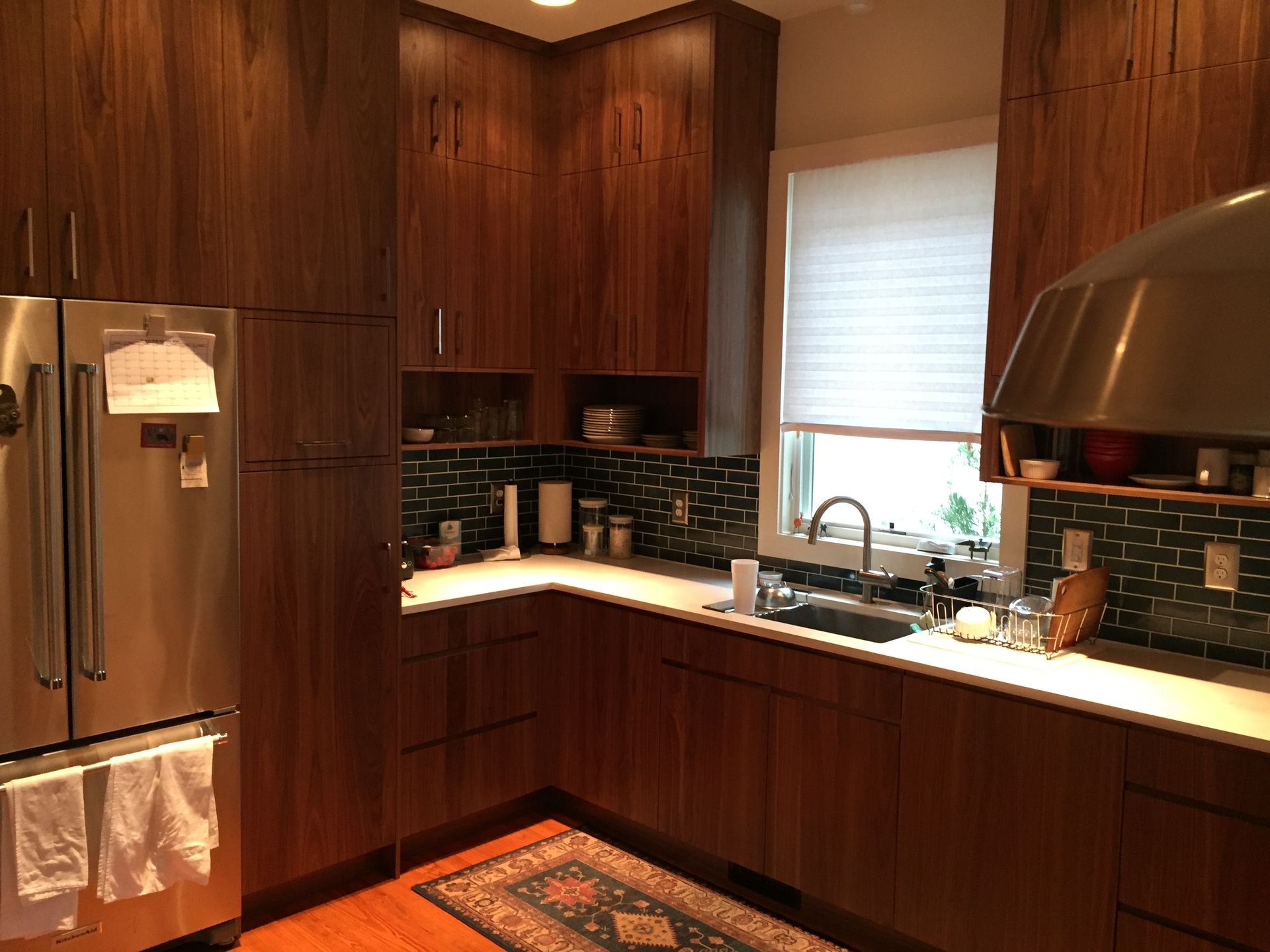 Modern kitchen with wood cabinets, stainless steel appliances, black tile backsplash, and a window over the sink