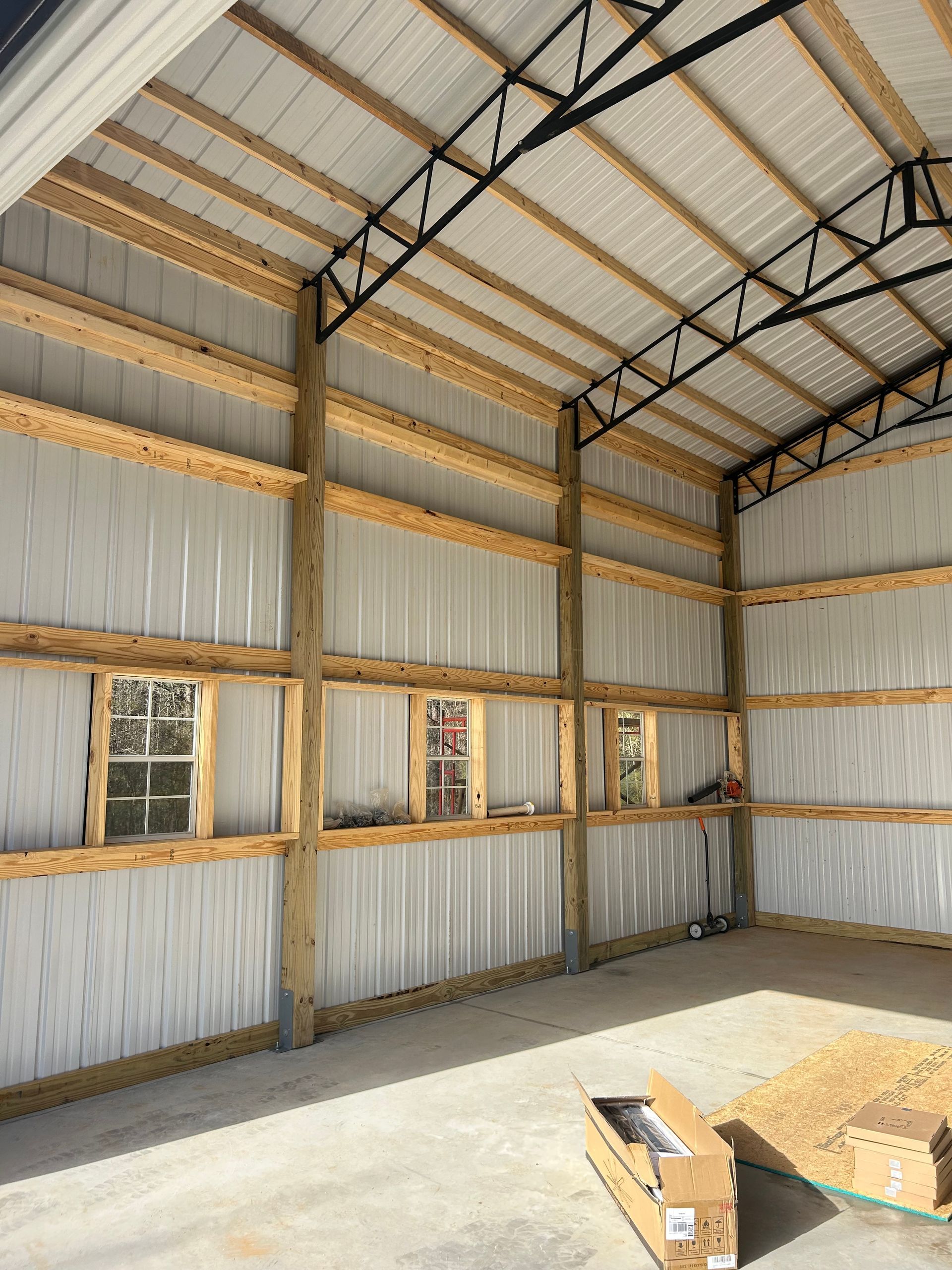 Empty metal workshop interior with corrugated walls, windows, and exposed roof trusses.