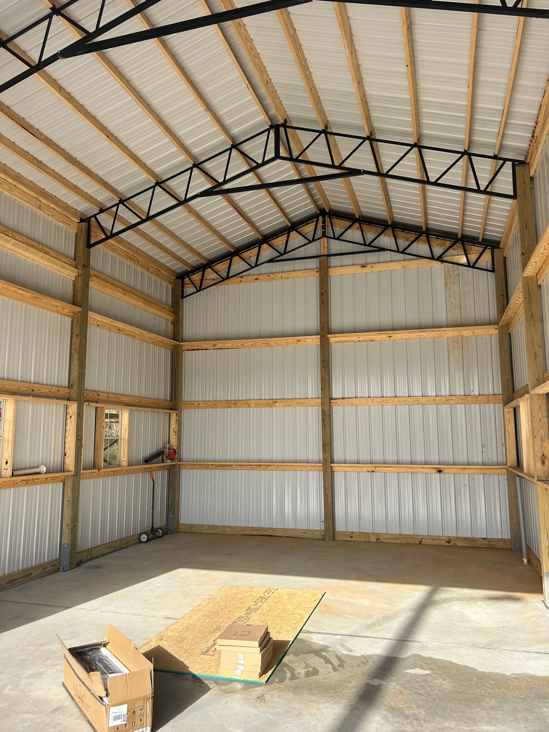 Empty metal shed interior with corrugated walls, concrete floor, and boxes near the entrance