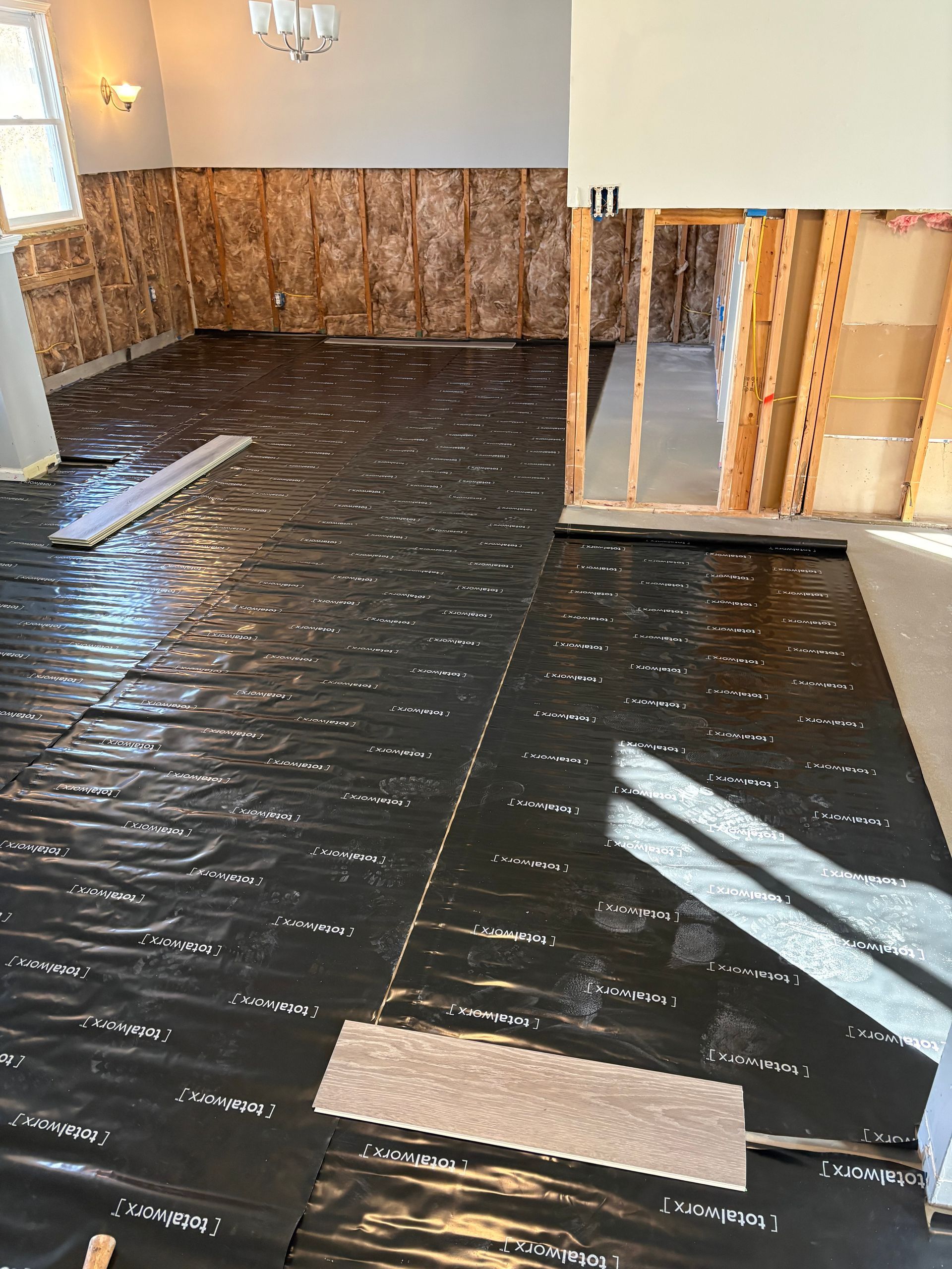 Empty room with black floor covering and brown wood-paneled wall section