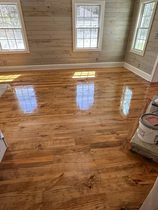 Glossy hardwood floor in a bright empty room with wood-paneled walls and windows