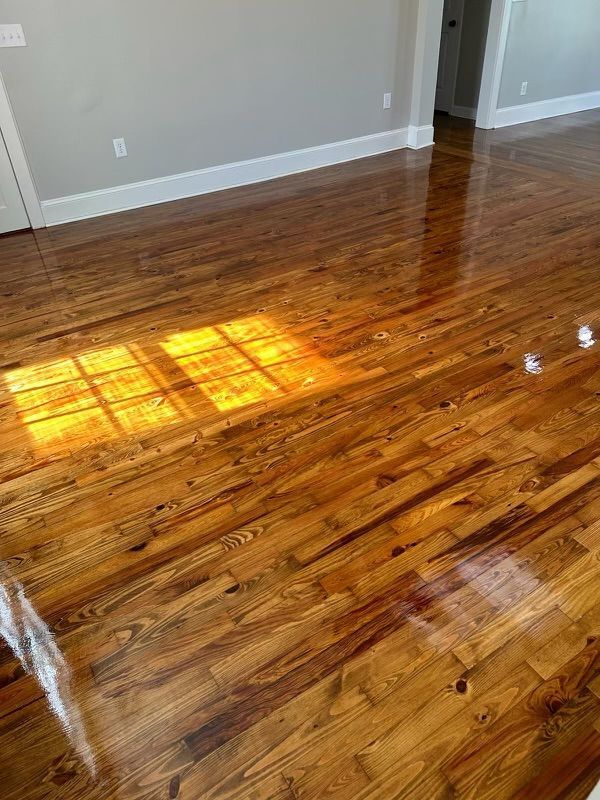 Empty room with glossy hardwood floor and sunlight reflecting across it