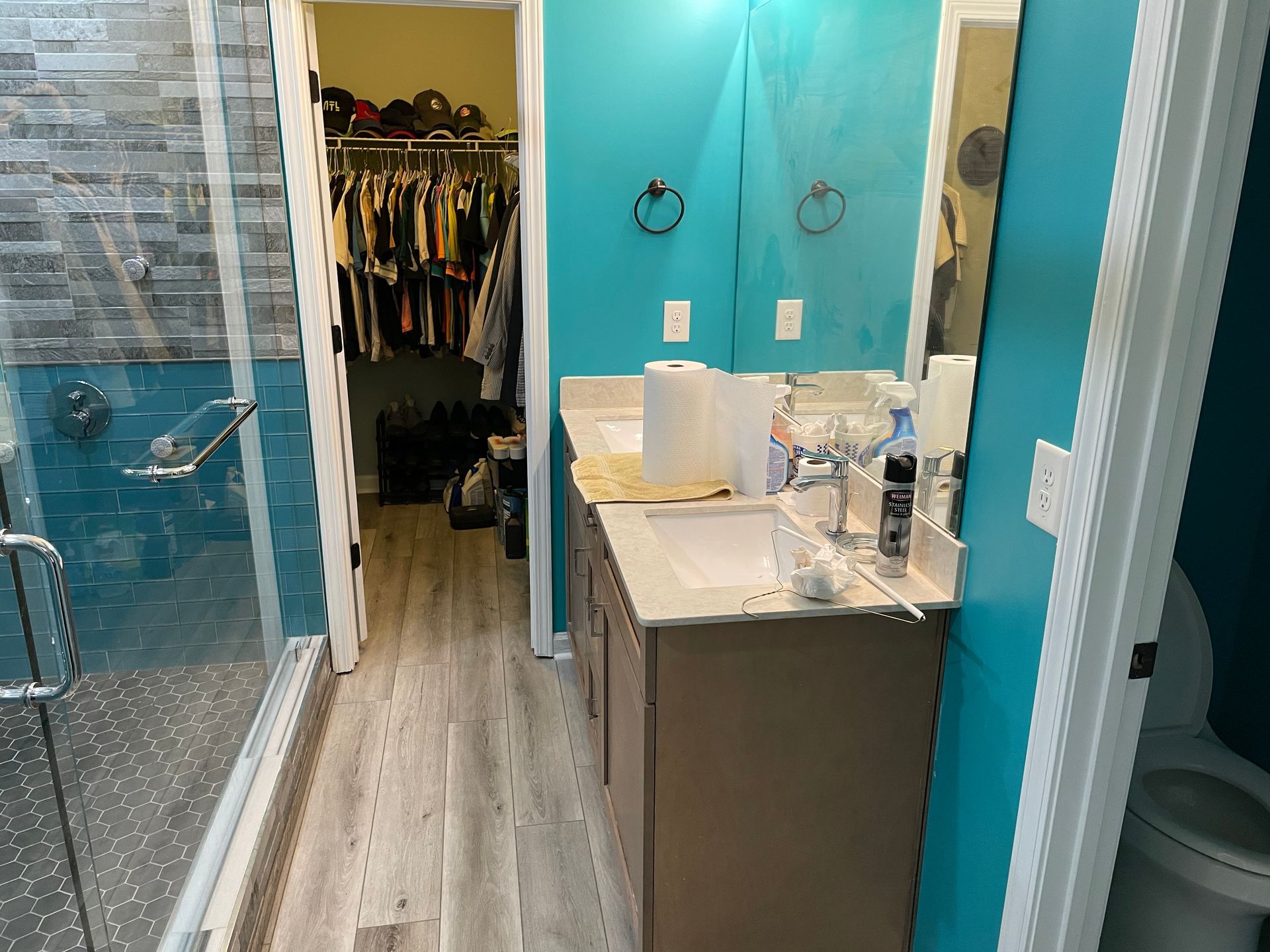 Bathroom with turquoise walls, vanity sink, and open closet doorway with clothes inside.