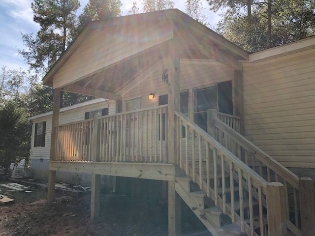 Wooden porch with stairs on a beige house in bright sunlight