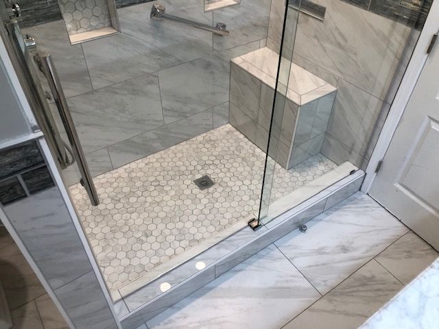 Glass shower enclosure with tiled floor and white marble bathroom floor