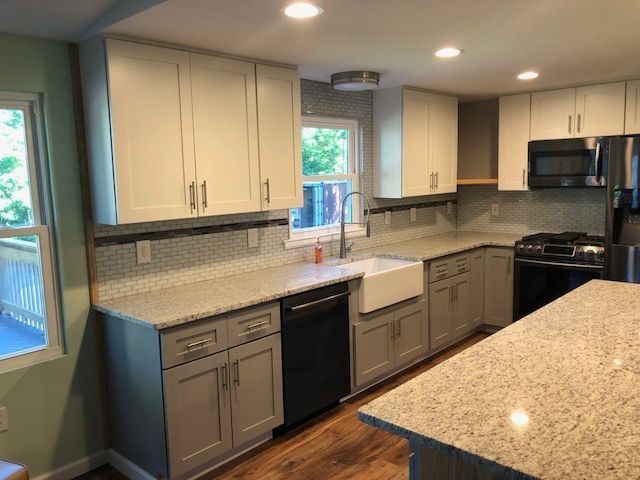 Modern kitchen with beige cabinets, granite counters, black appliances, and a peninsula under bright lights