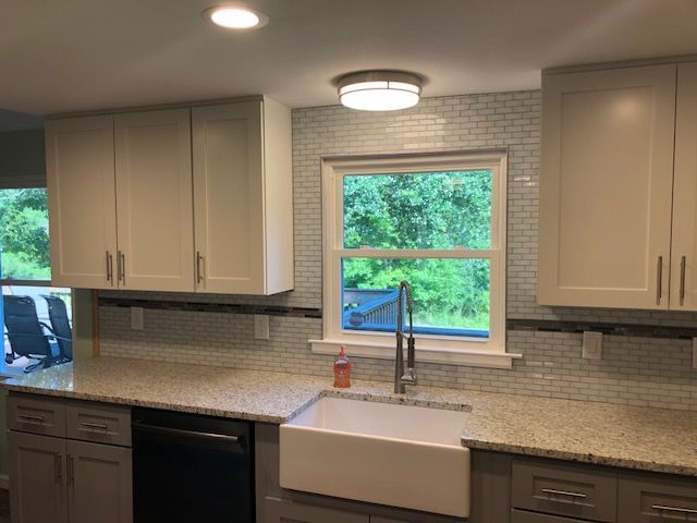 Modern kitchen with beige cabinets, granite counters, white farmhouse sink, and window above the sink