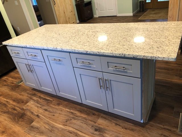 Large kitchen island with white cabinets and speckled granite countertop in a modern kitchen