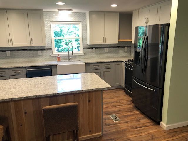 Bright modern kitchen with white cabinets, black appliances, and a large island with granite countertop.
