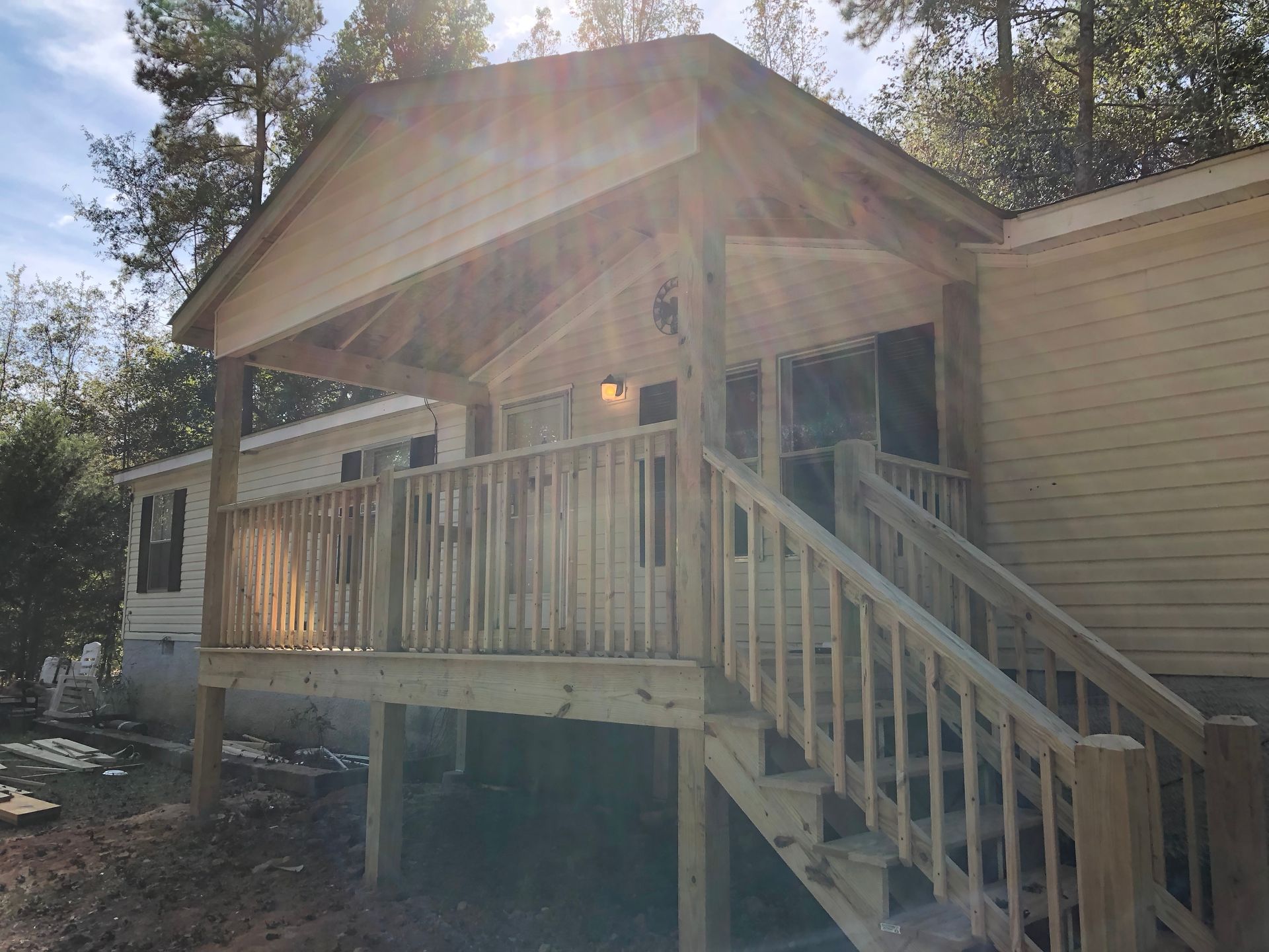 Wooden front porch with stairs and railing on a beige house in bright sunlight
