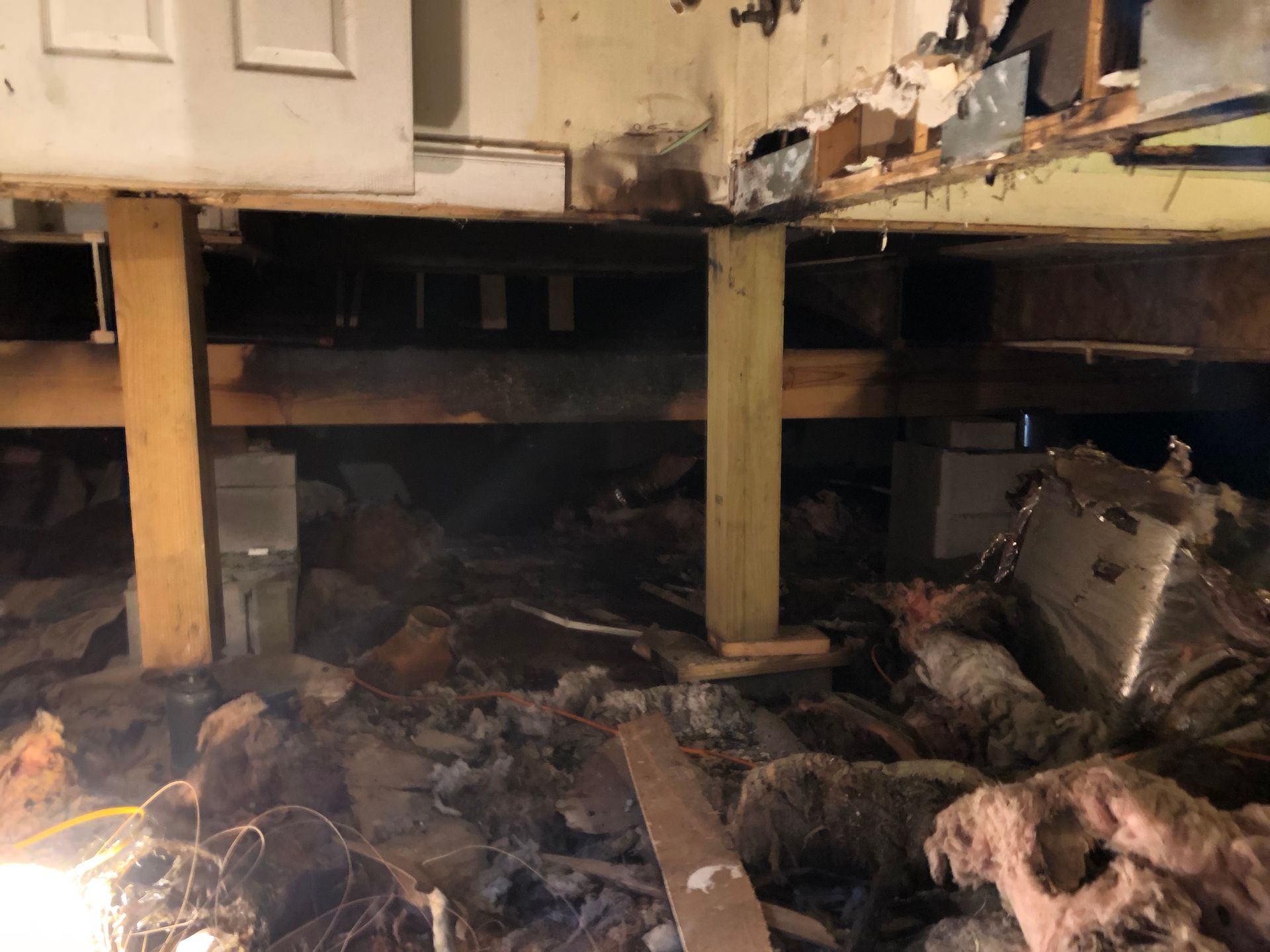 Fire-damaged room with charred debris and smoke stains under elevated cabinets